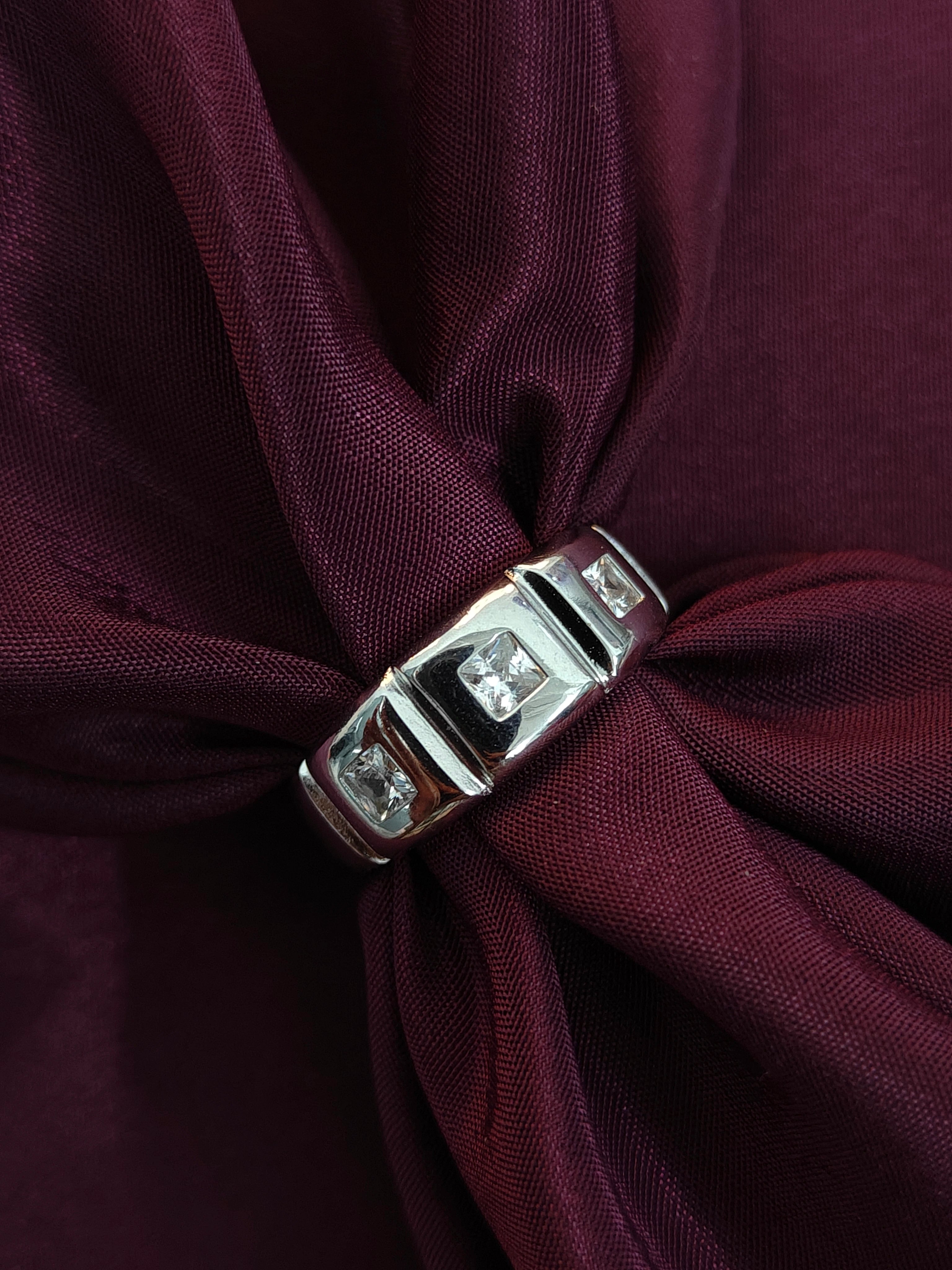 Close-up of a silver clasp on a burgundy fabric