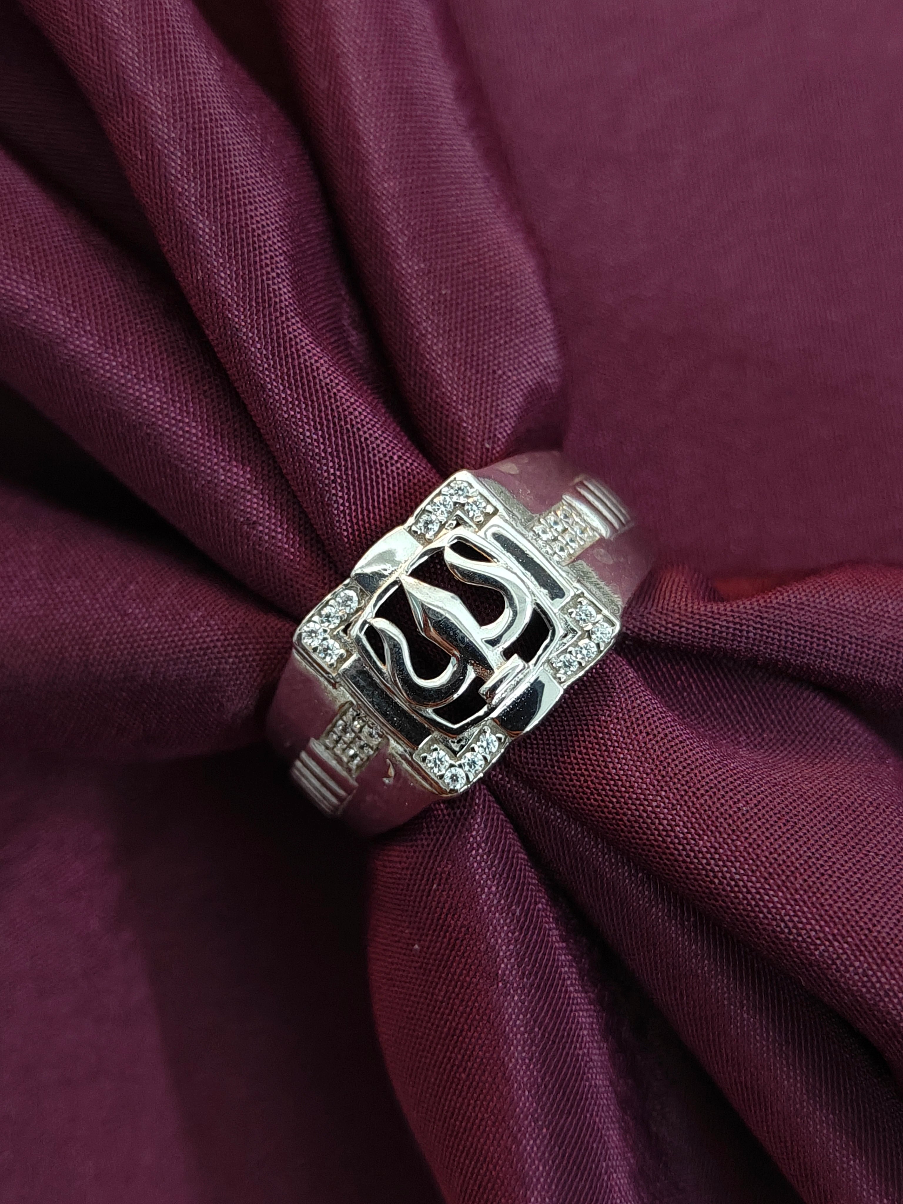 Silver ring with a decorative design on a purple fabric background