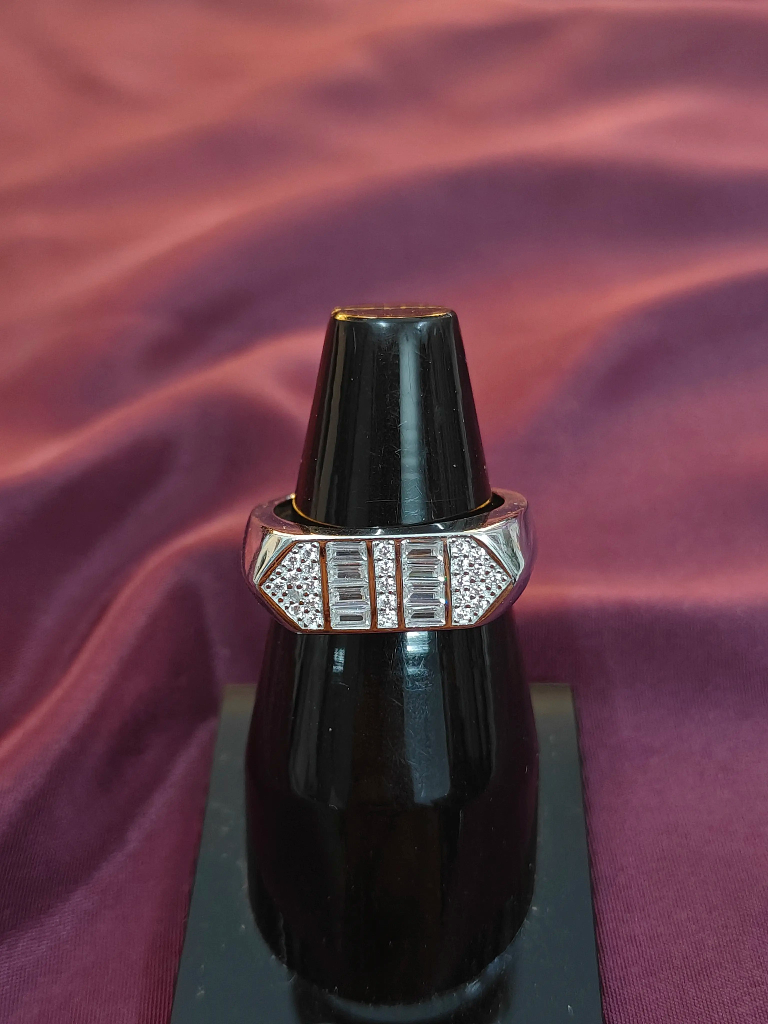 Ring with diamond accents on a black stand against a purple fabric background