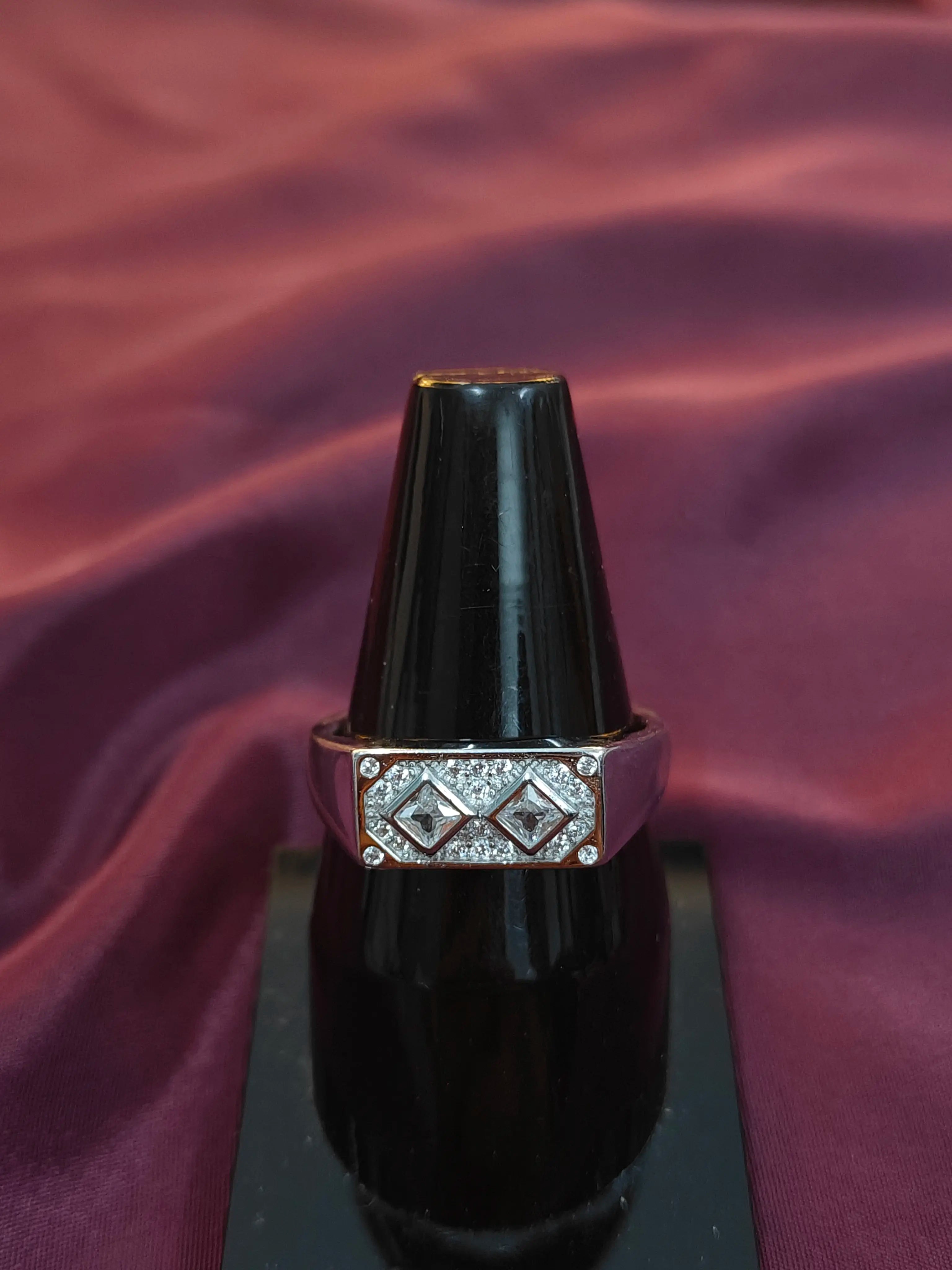 Black ring with diamond-like stones on a purple fabric background