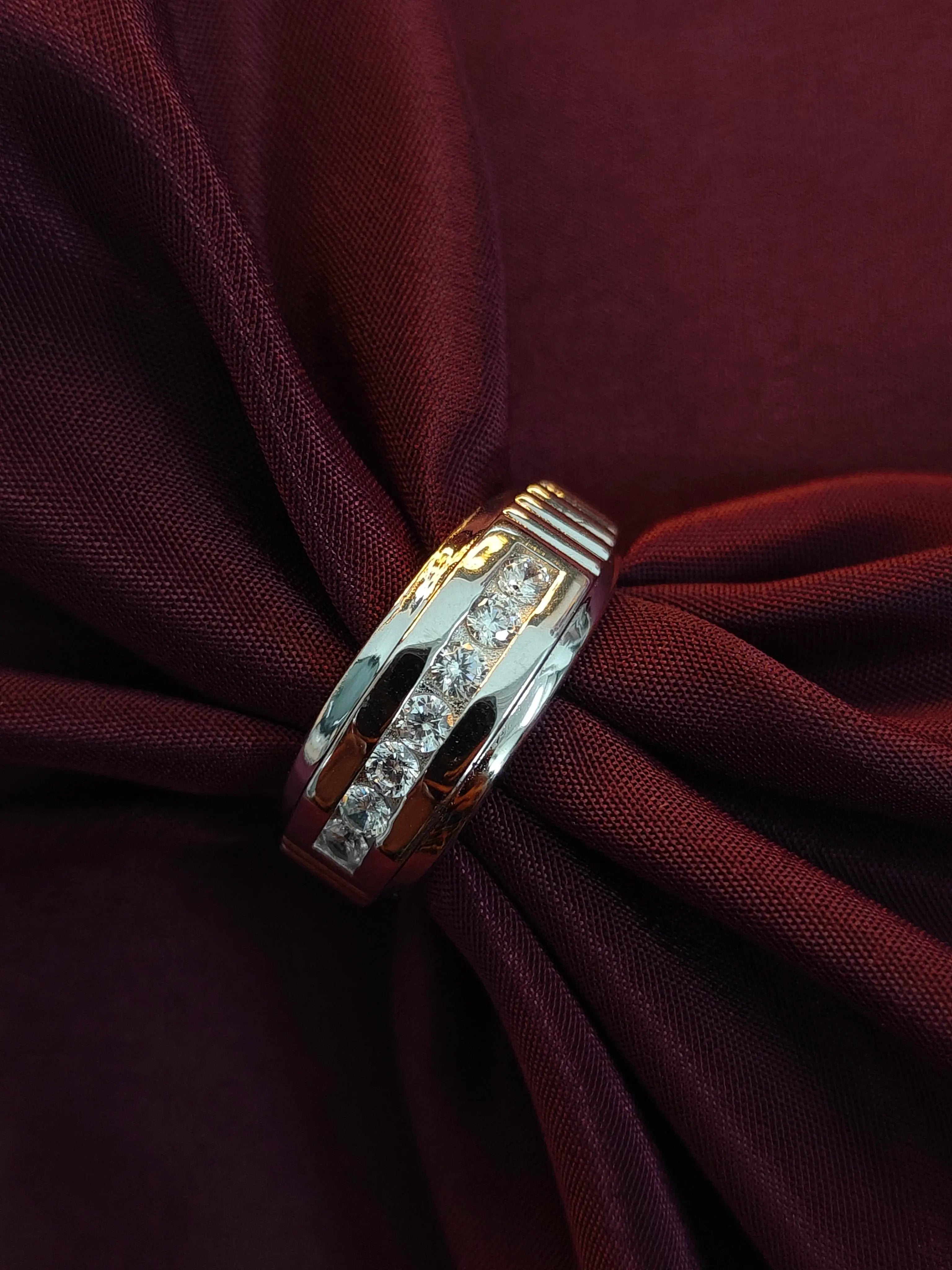 Gold ring with diamonds on a maroon fabric background