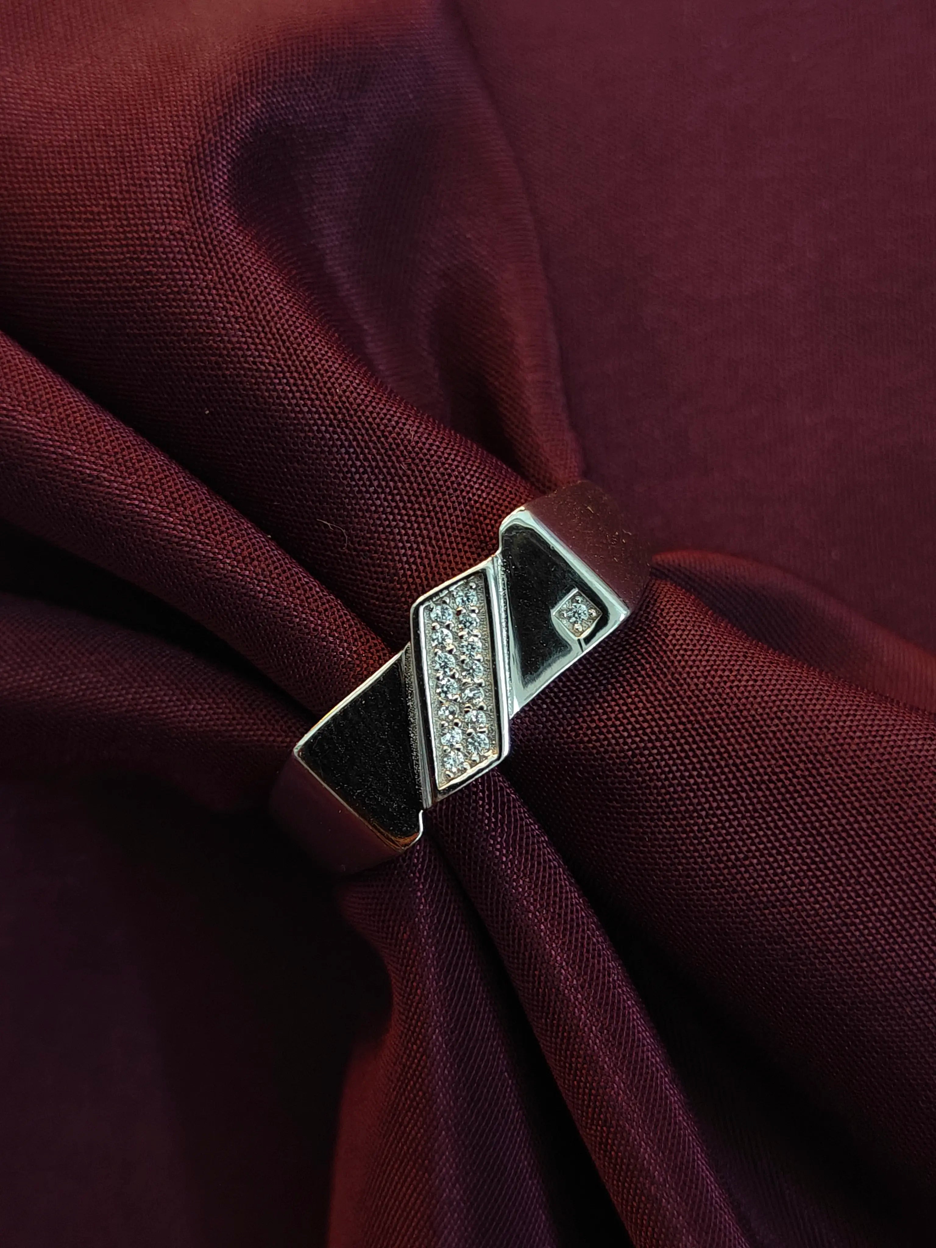 Silver brooch with gemstones on a burgundy fabric background