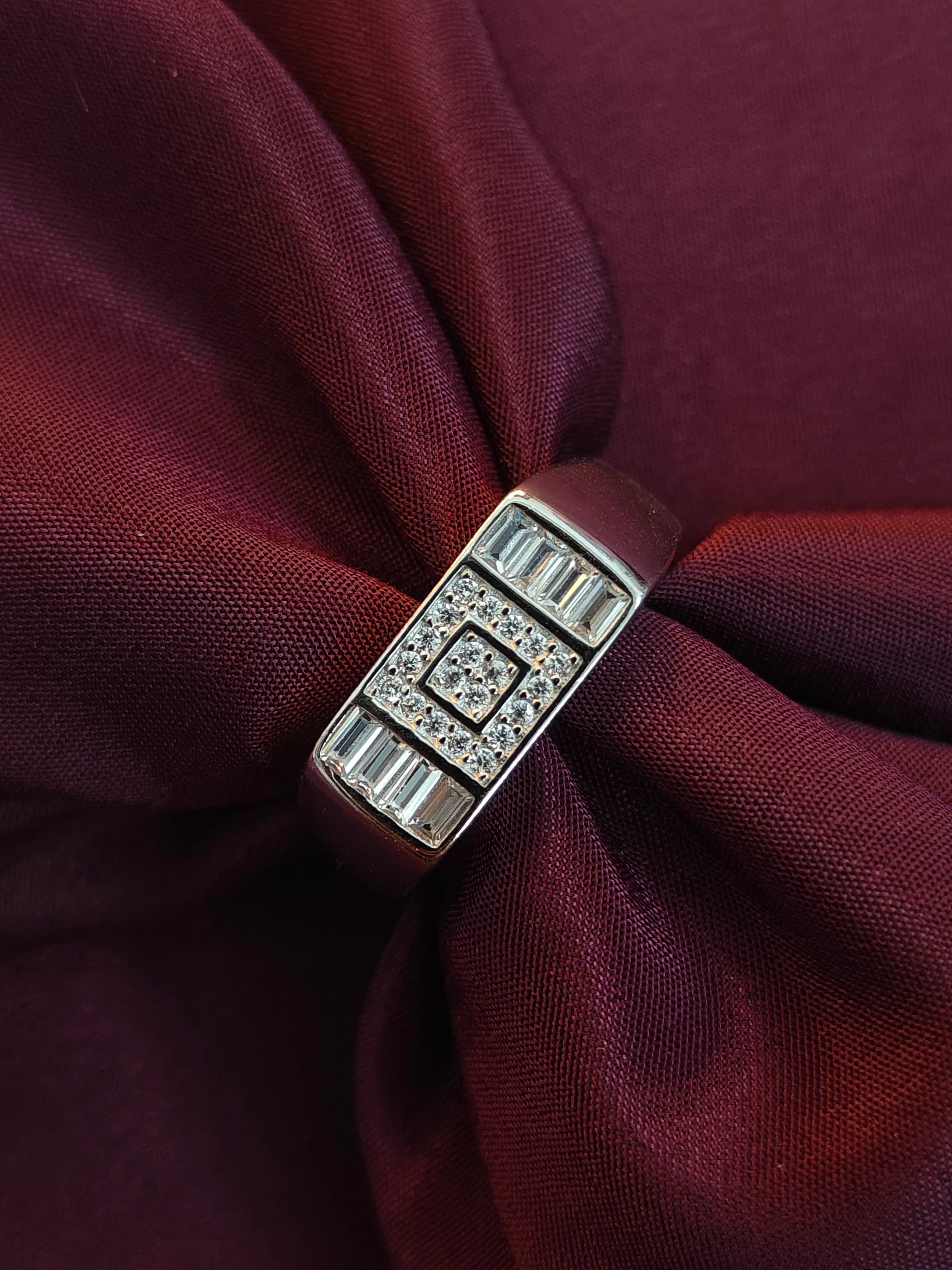 Silver ring with gemstones on a maroon fabric background