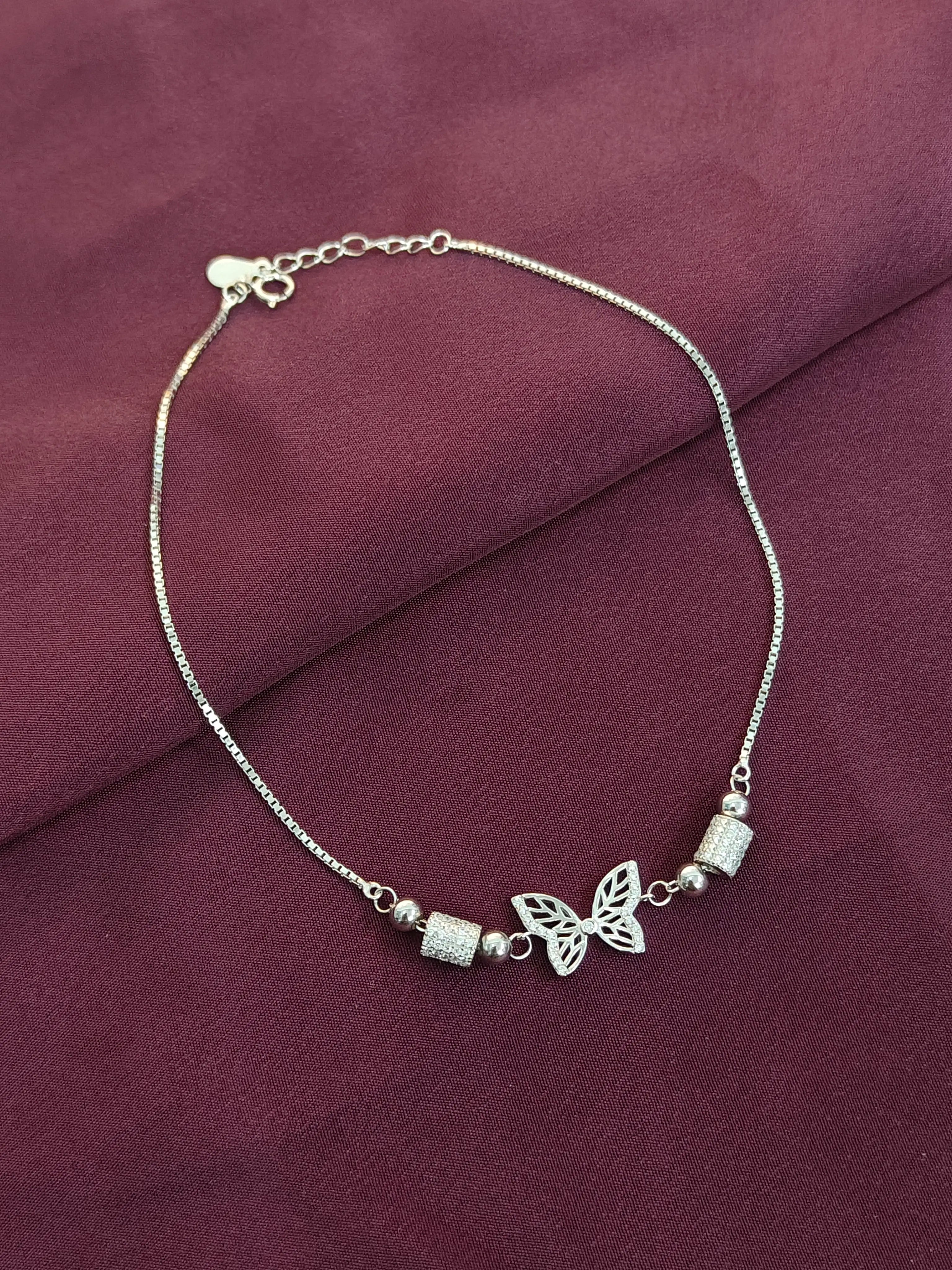 Silver butterfly bracelet on a burgundy fabric background