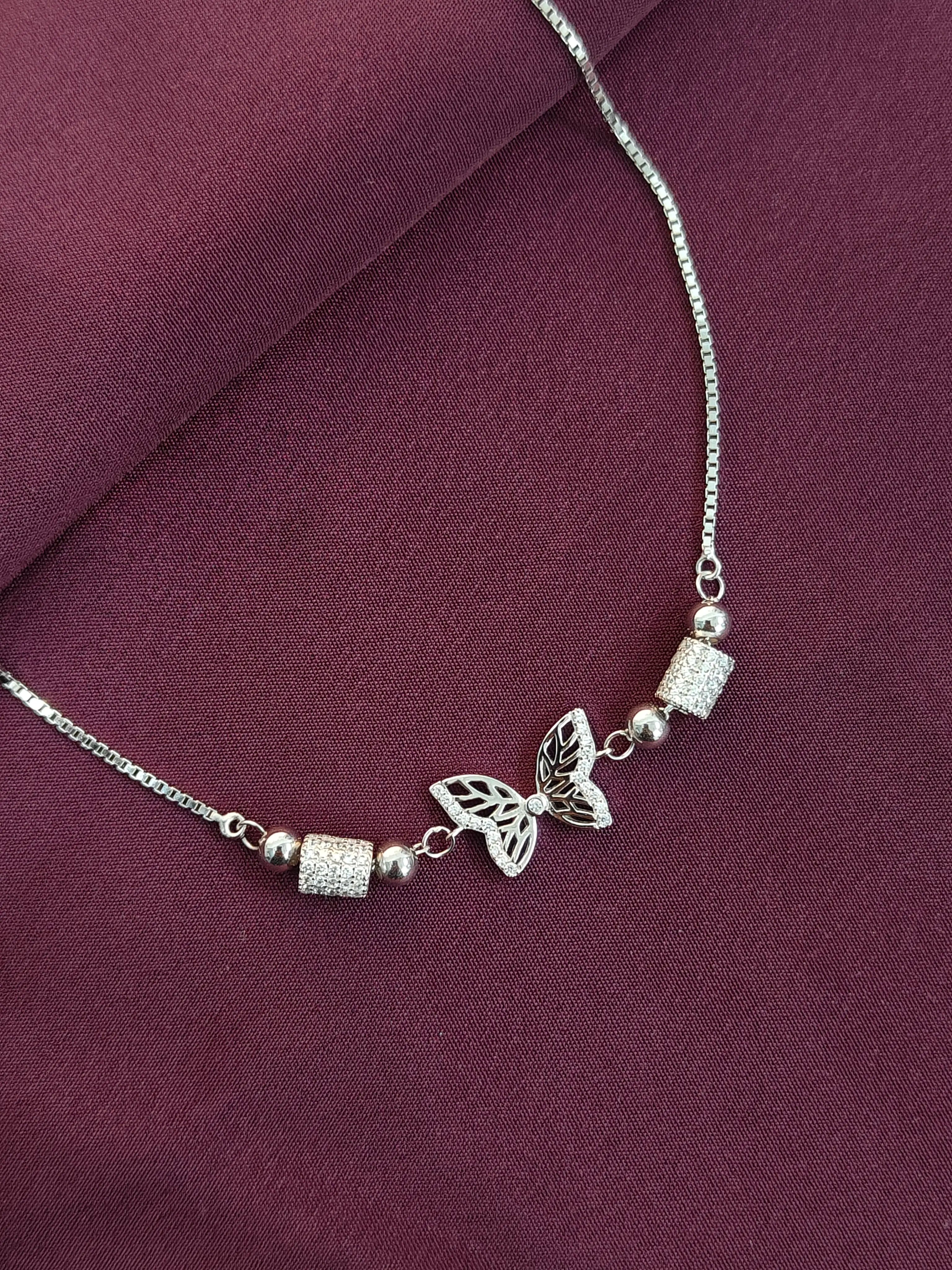 Silver necklace with butterfly pendant on a purple fabric background