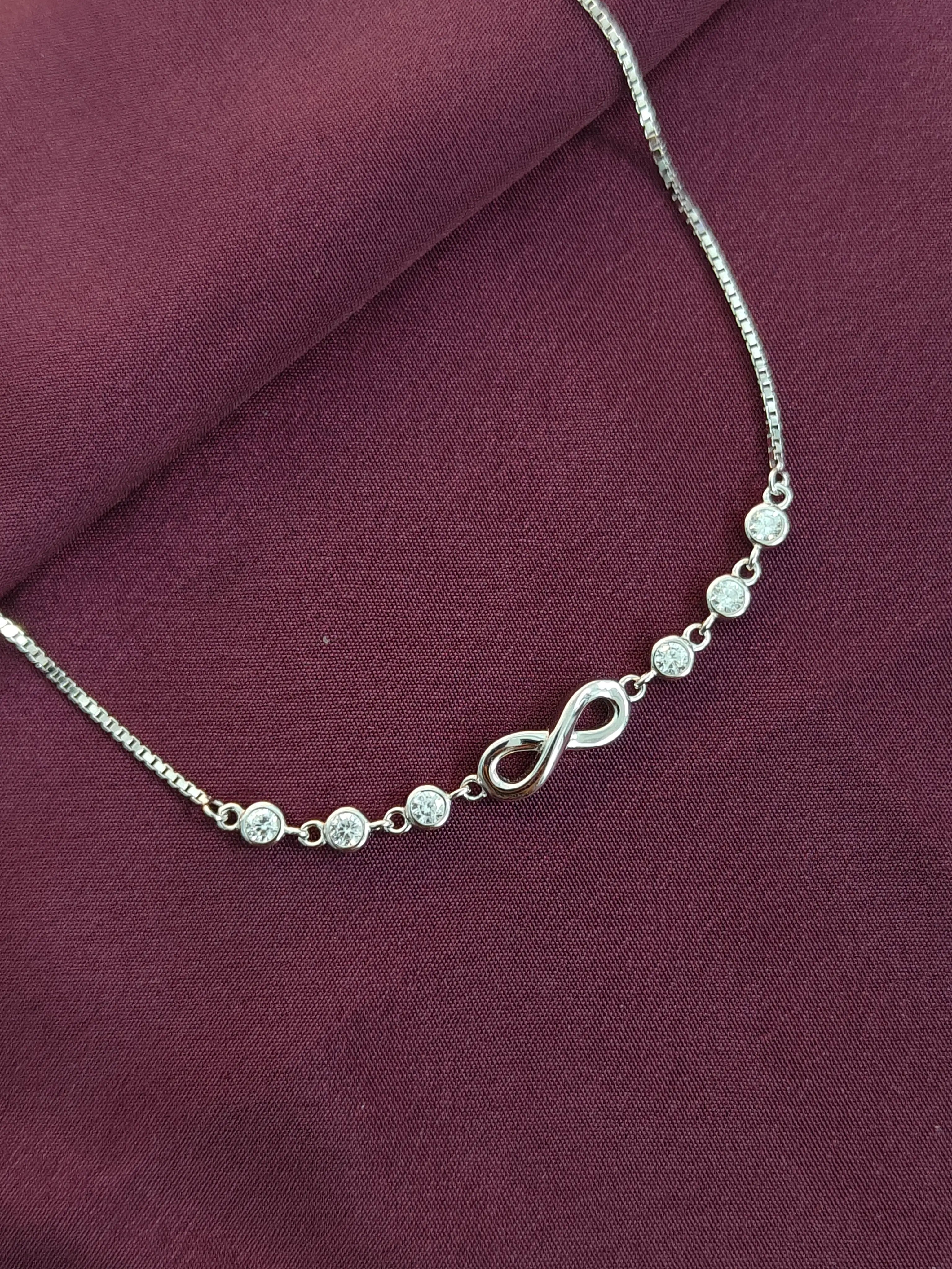 Silver necklace with diamond-like beads on a purple fabric background