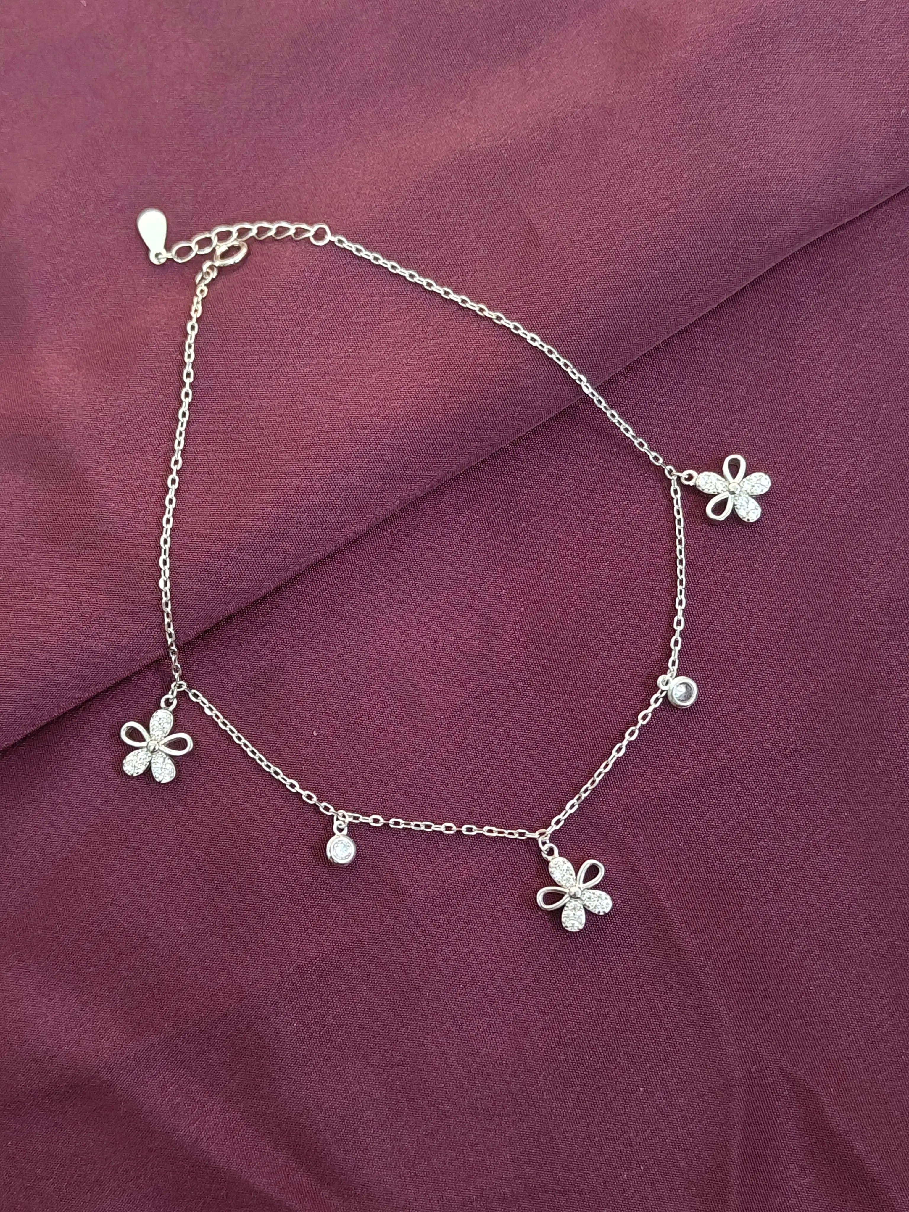 Silver anklet with butterfly charms on a purple fabric background