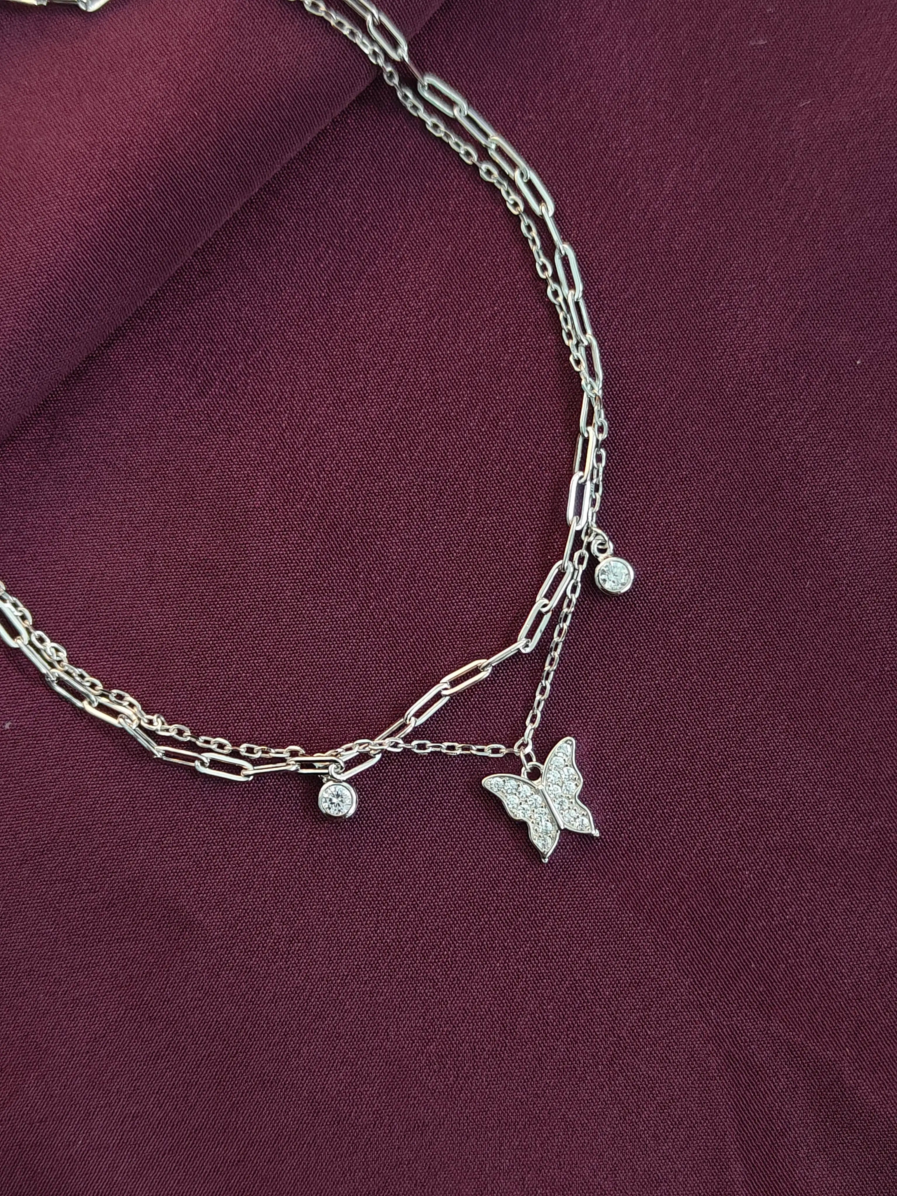 Silver chain necklace with butterfly pendant on a purple fabric background