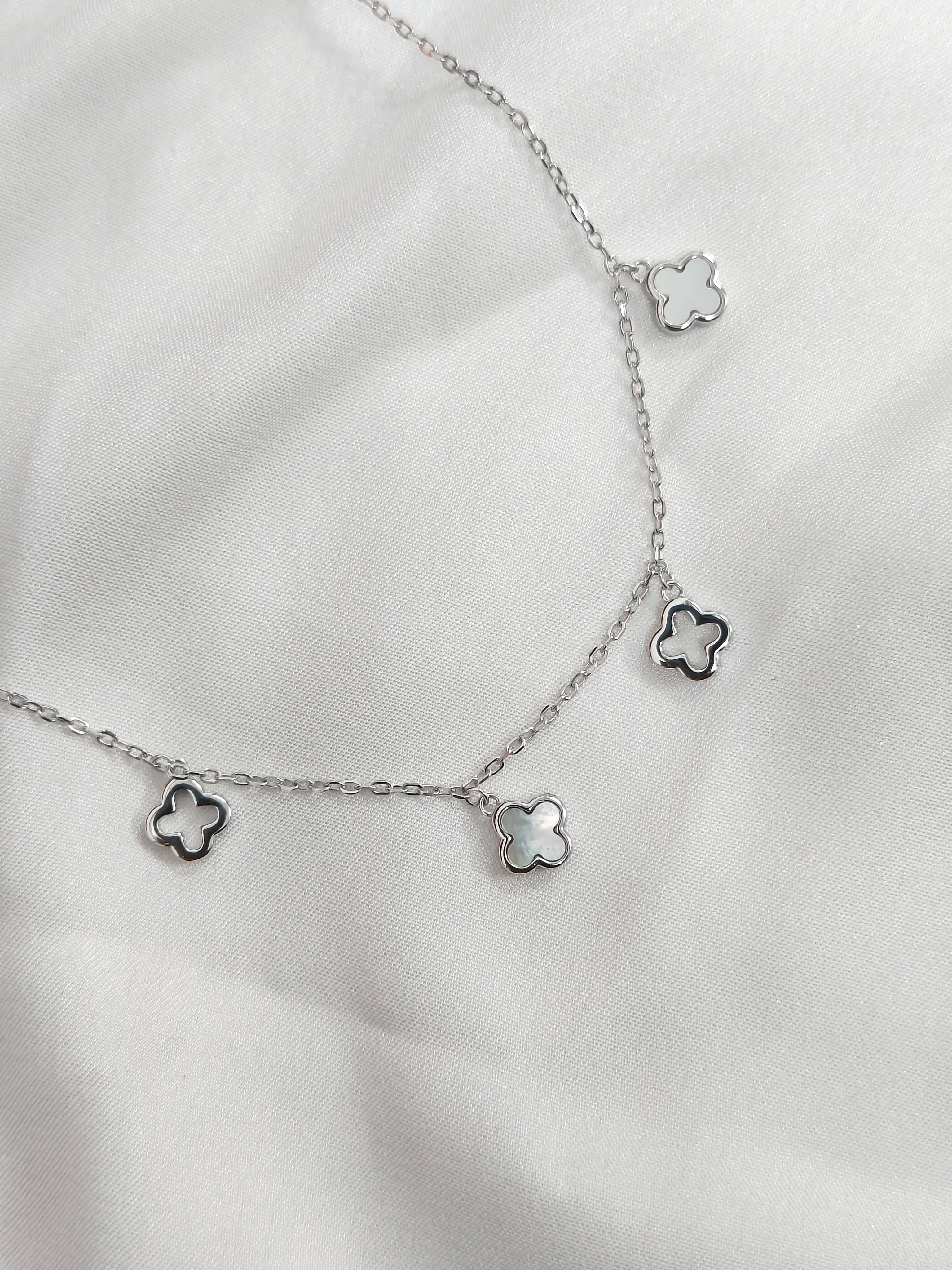 Silver necklace with star-shaped pendants on a white fabric background
