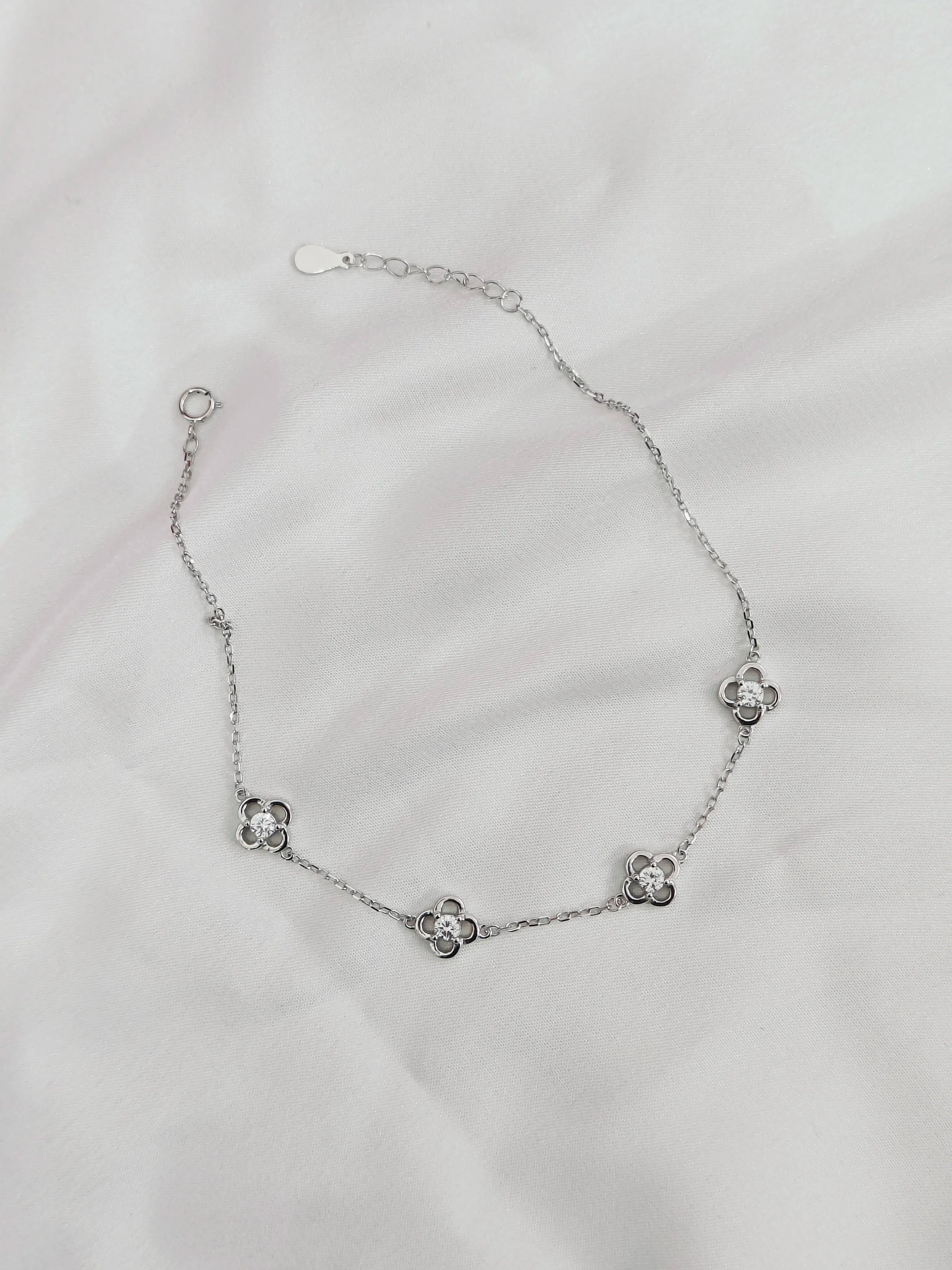 Silver bracelet with floral designs on a light gray background