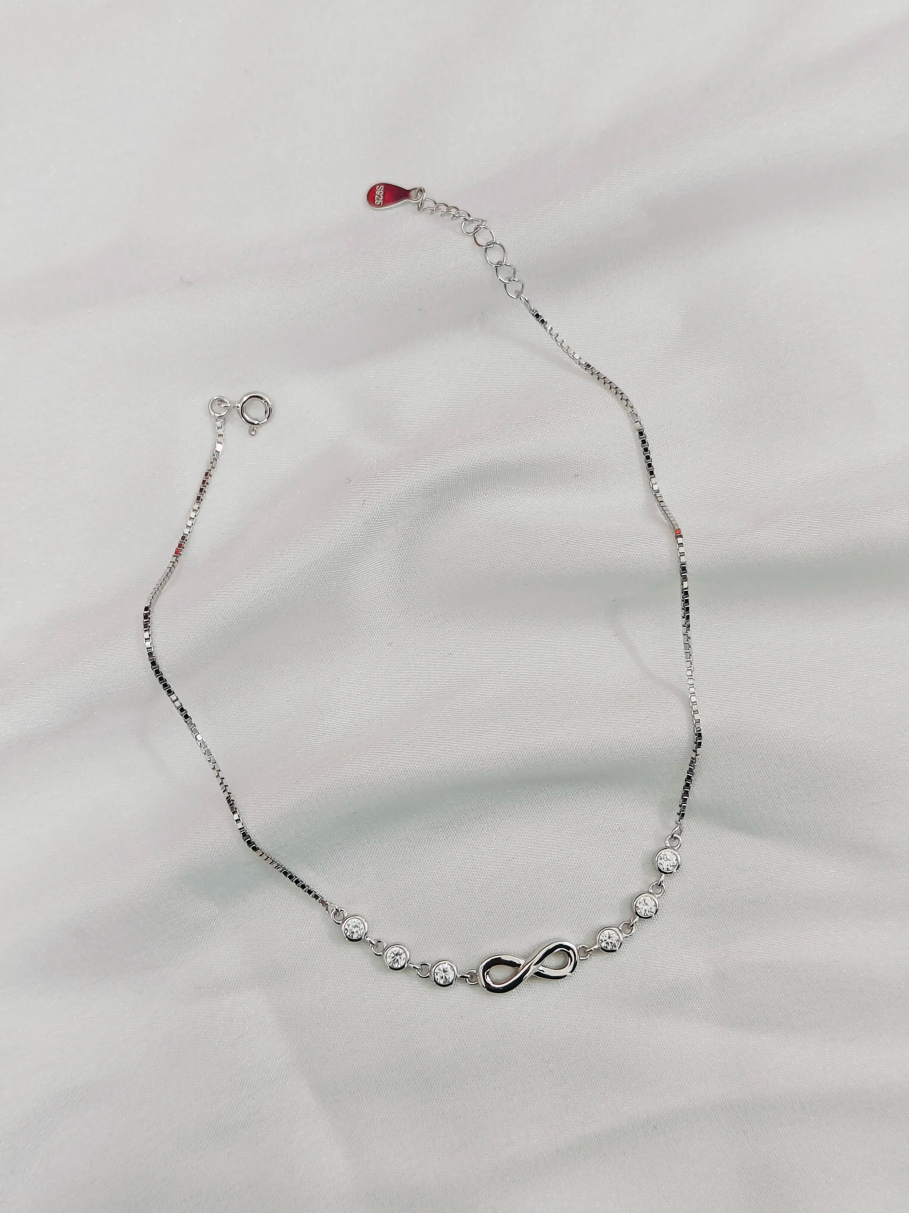 Silver necklace with infinity symbol on a light gray background