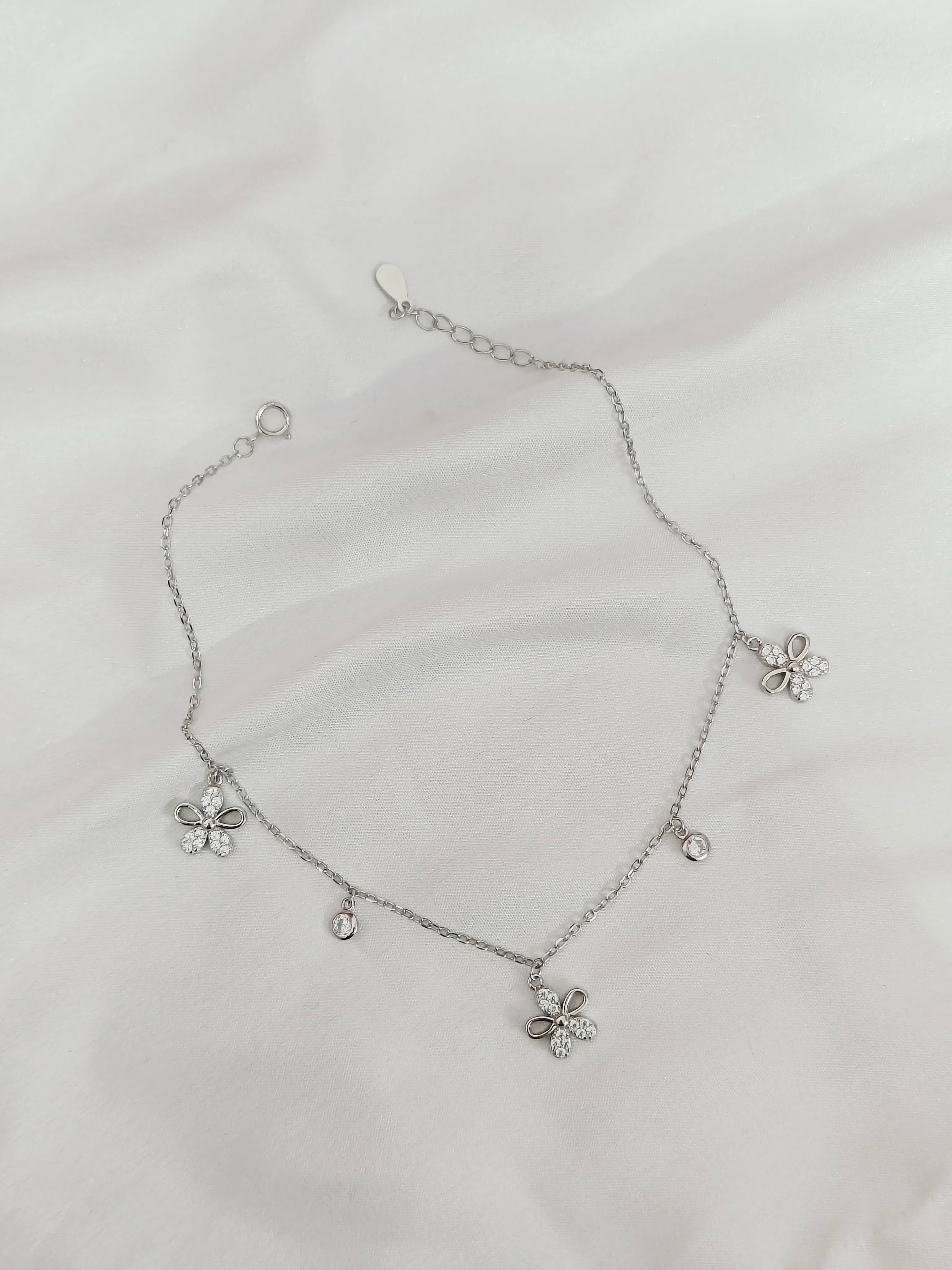 Silver necklace with flower-shaped pendants on a light gray background