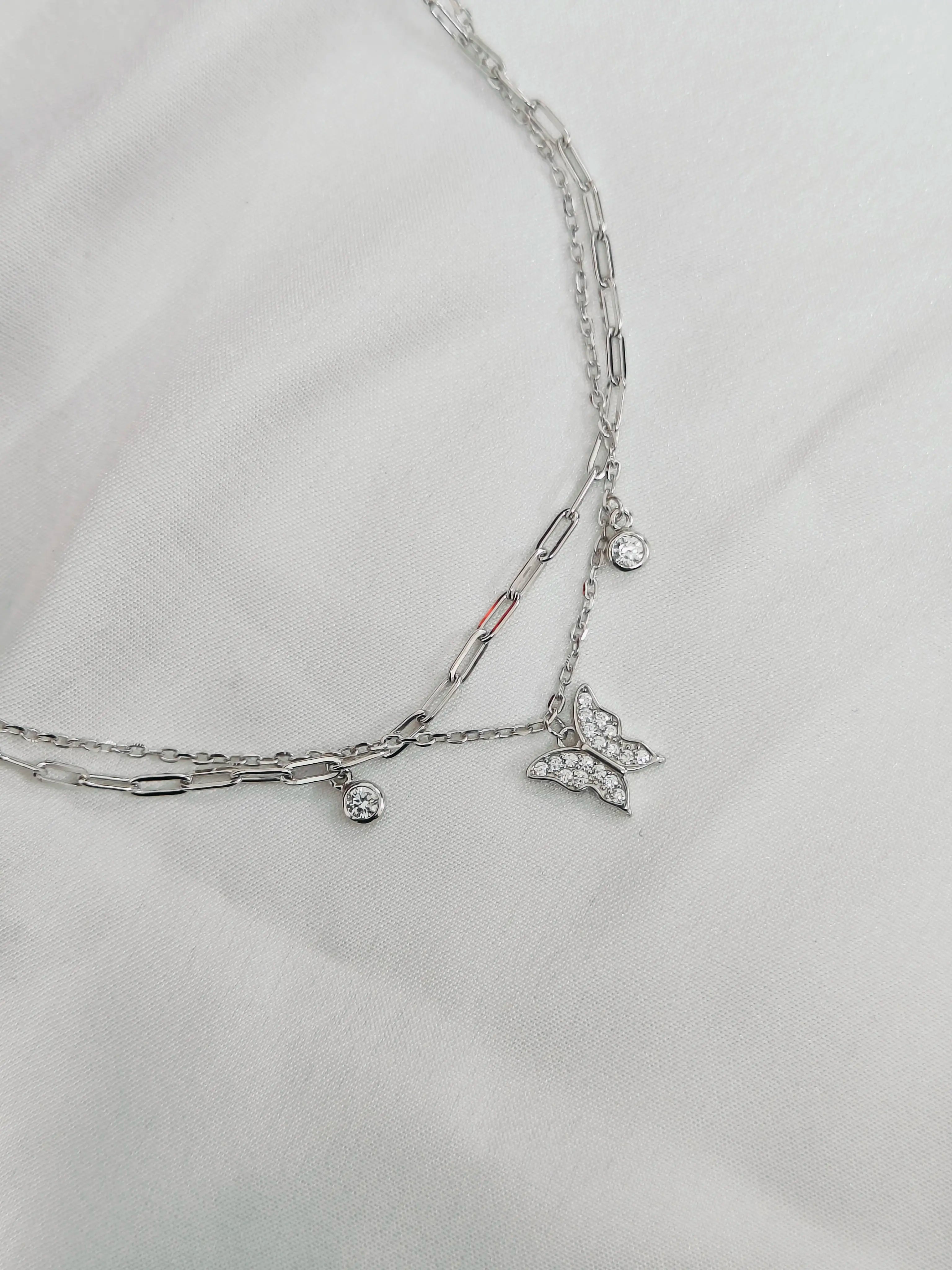 Silver chain necklace with charms on a light gray background
