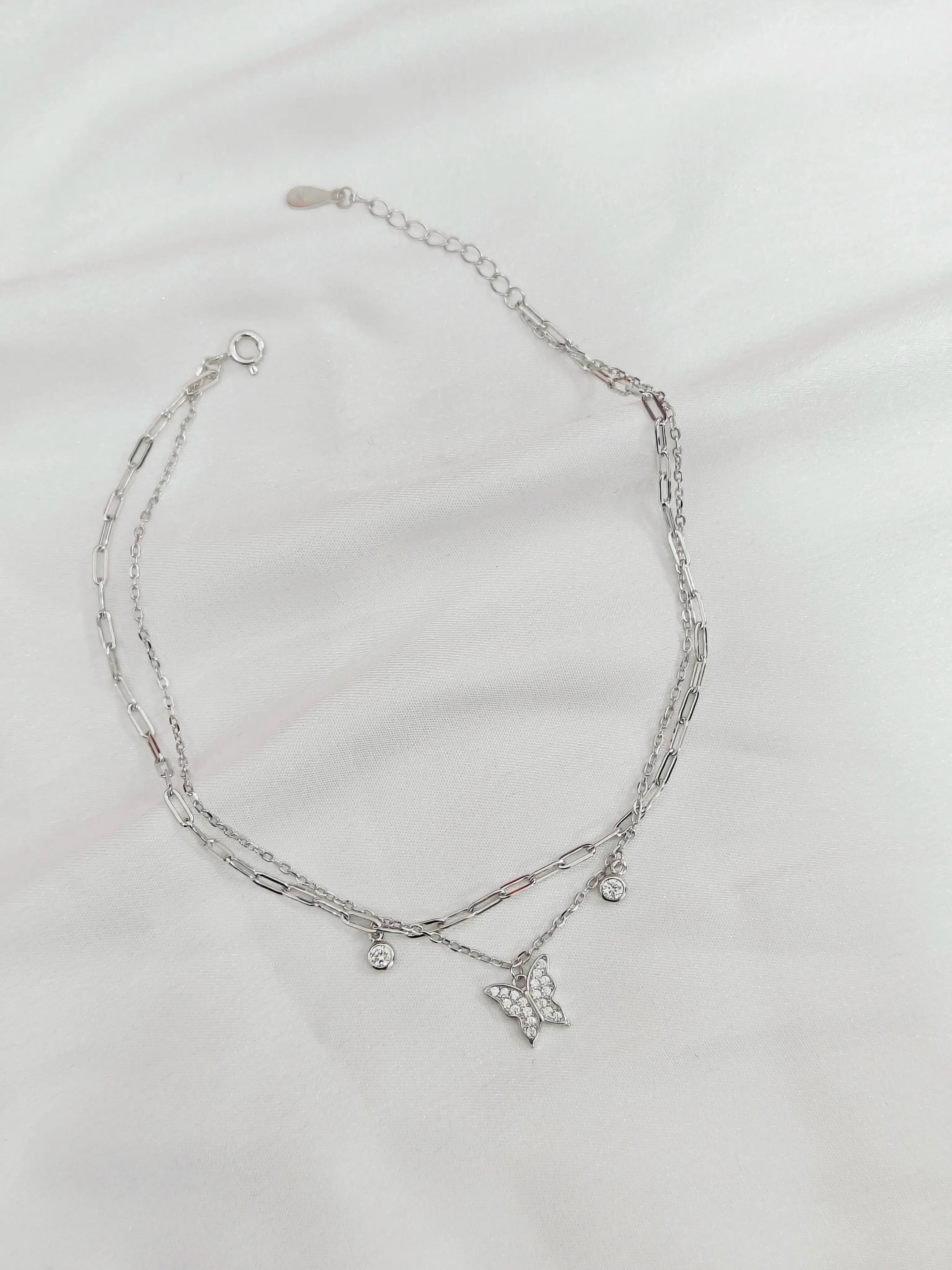 Silver necklace with a butterfly pendant on a light gray background