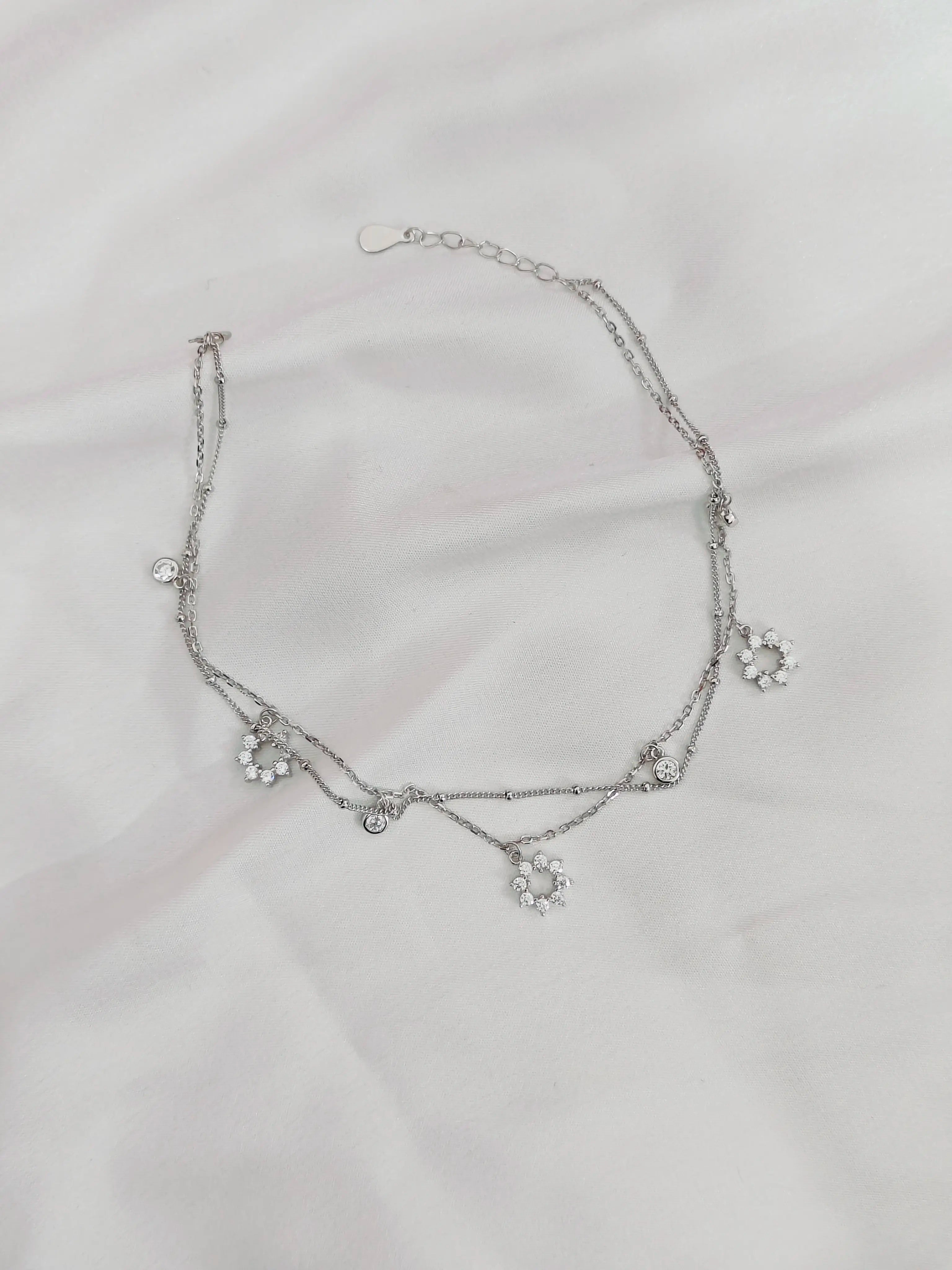 Silver necklace with floral designs on a light gray background