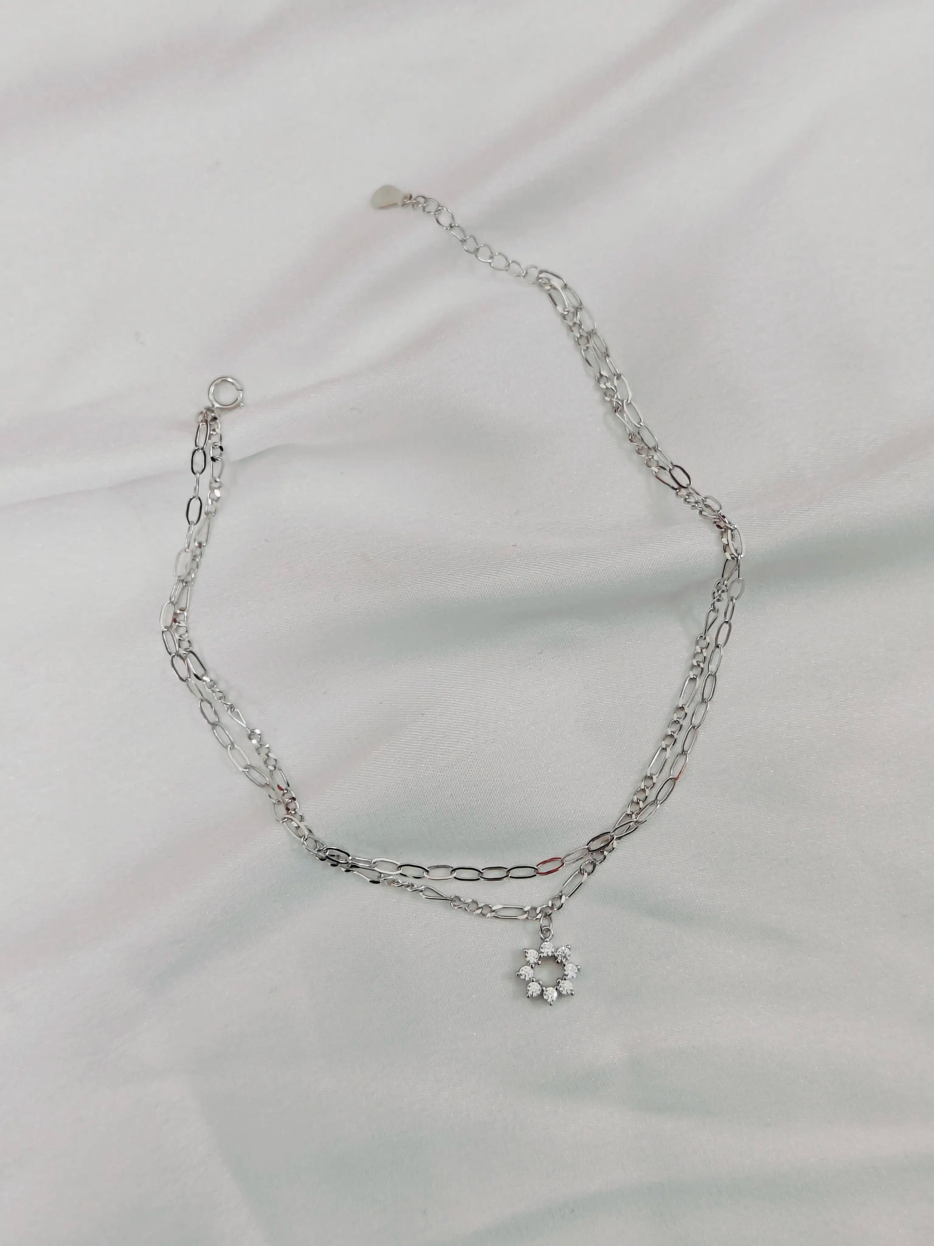 Silver chain necklace on a light gray fabric background