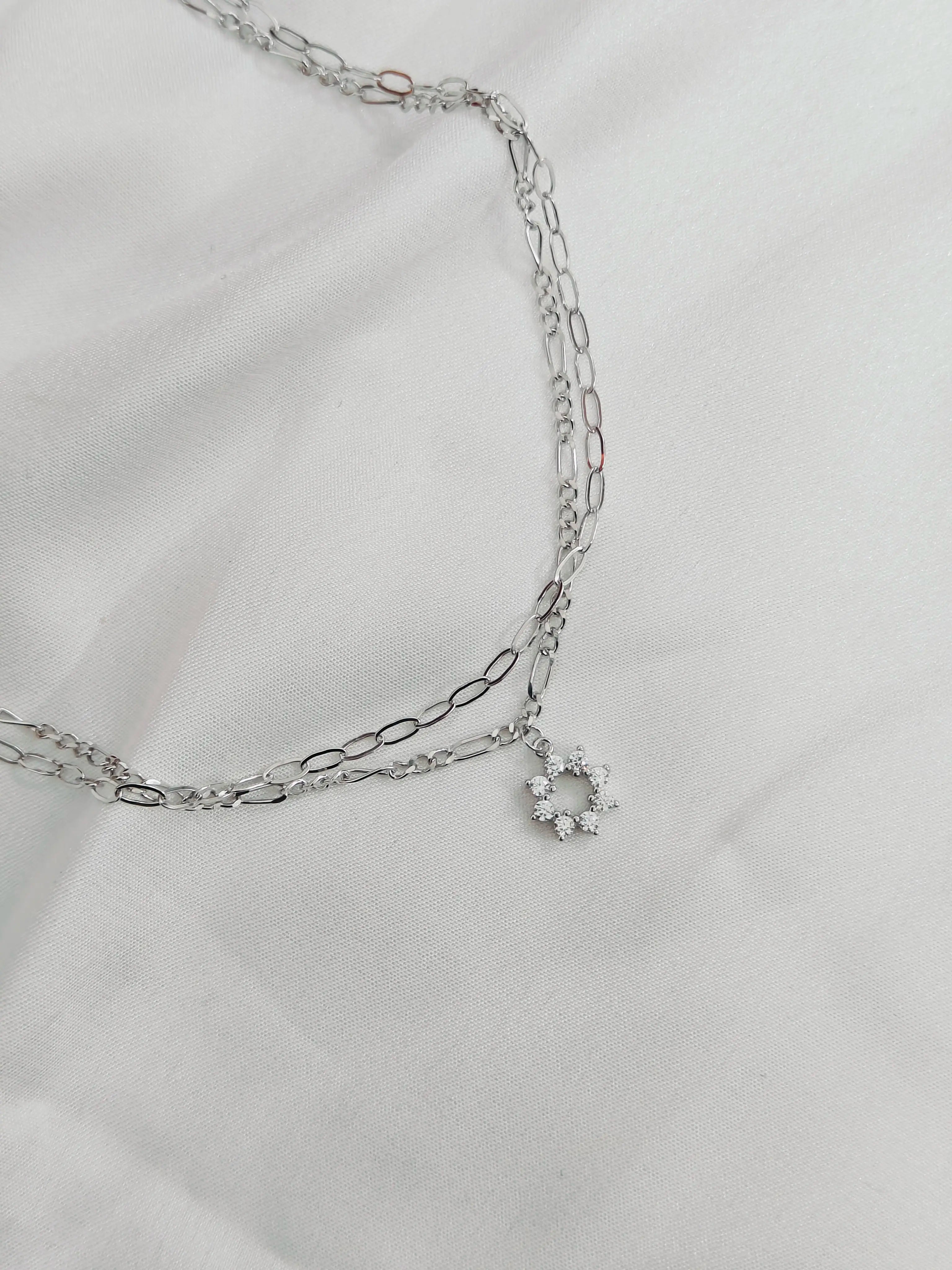 Silver chain necklace with a small round pendant on a light gray background