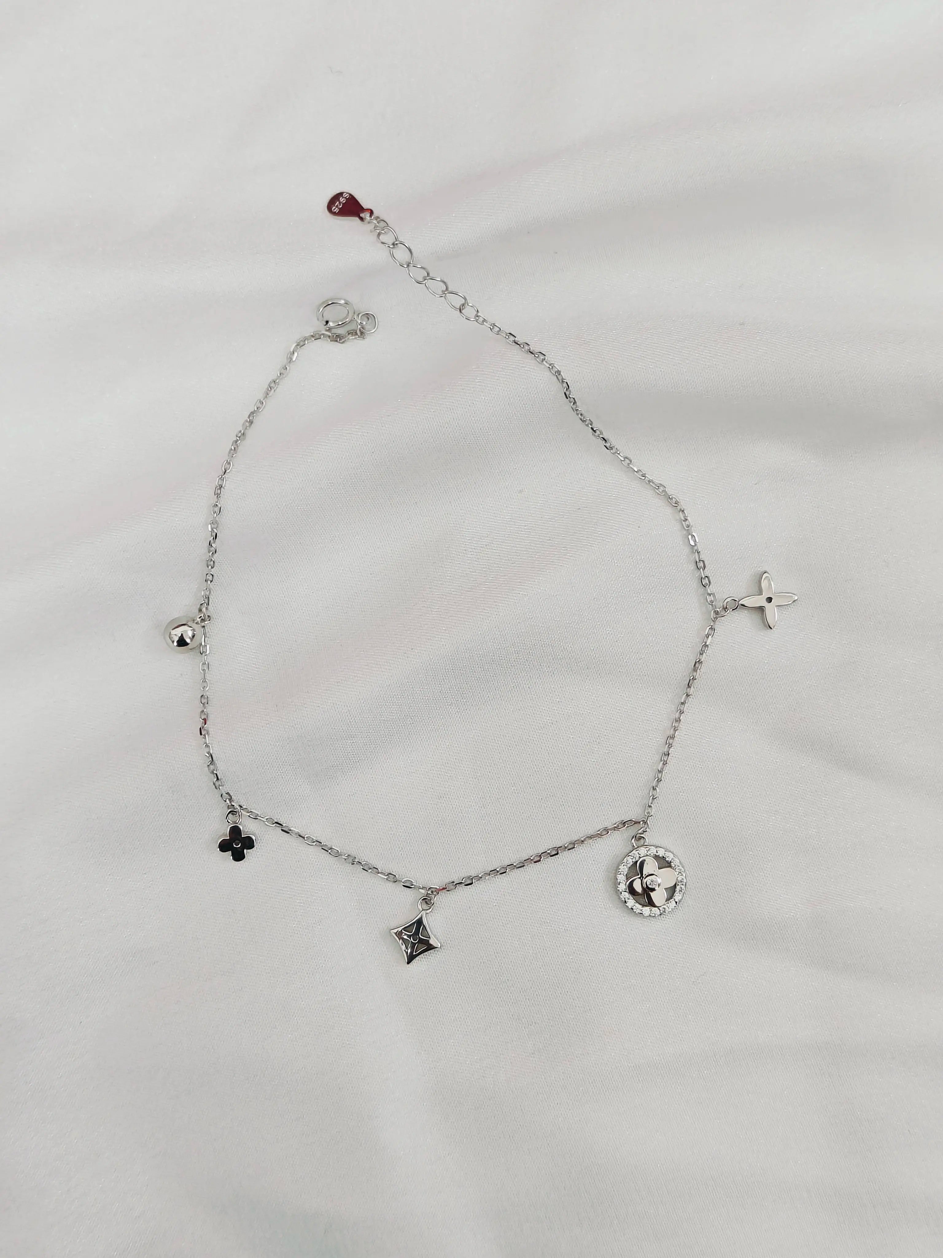 Silver bracelet with various charms on a light gray background