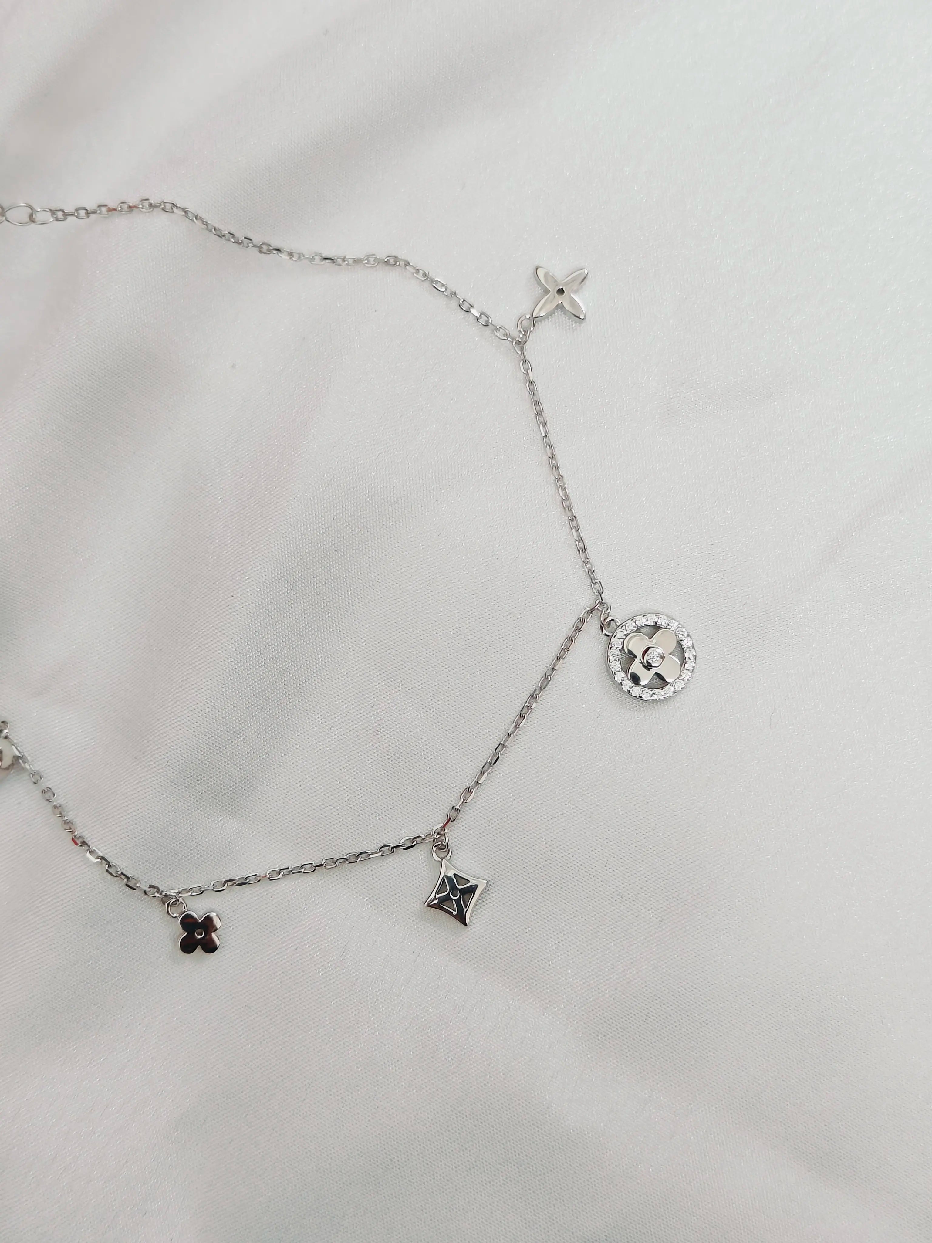 Silver necklace with charms on a light gray background