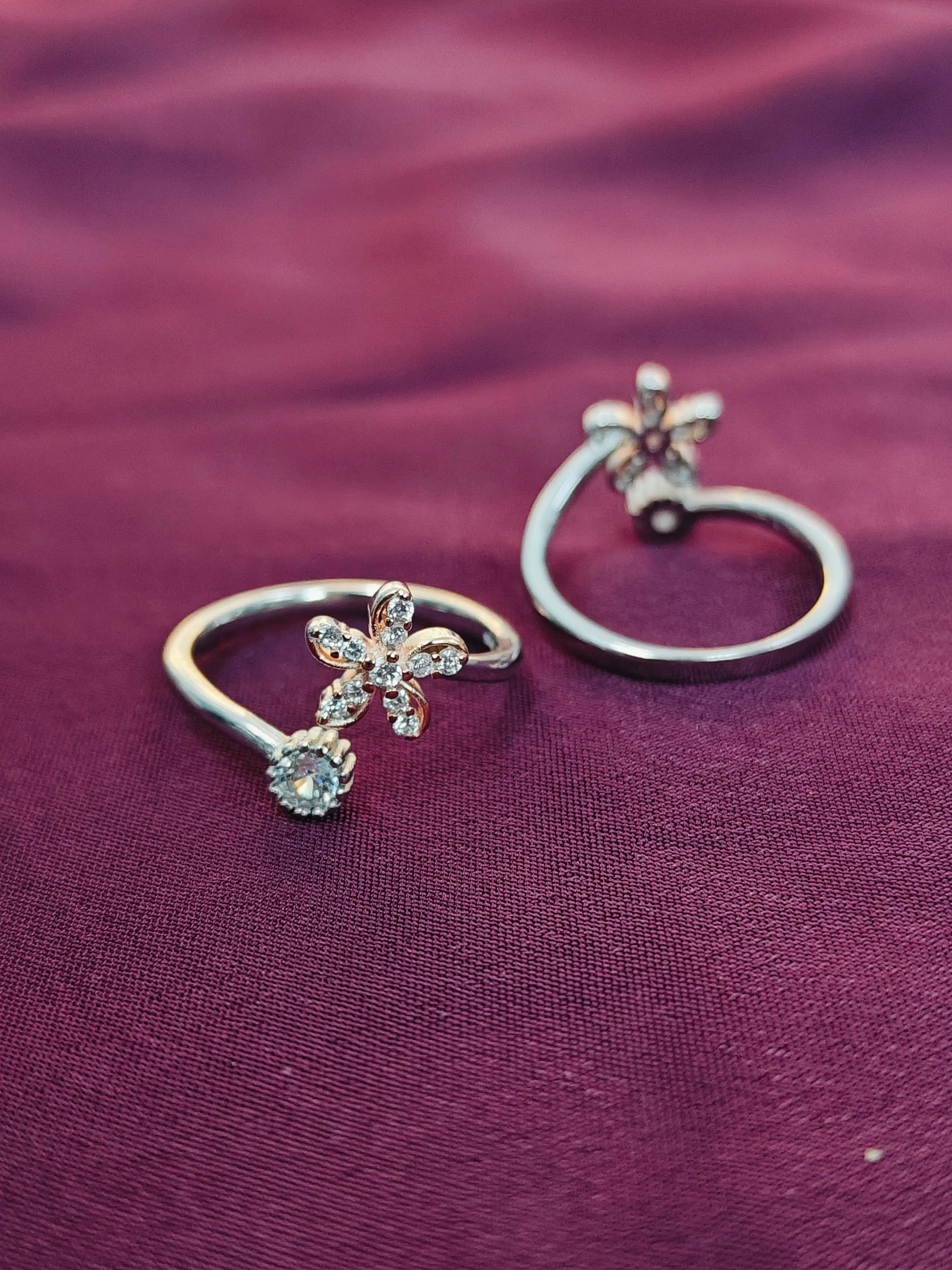 Two silver rings with floral designs on a purple fabric background