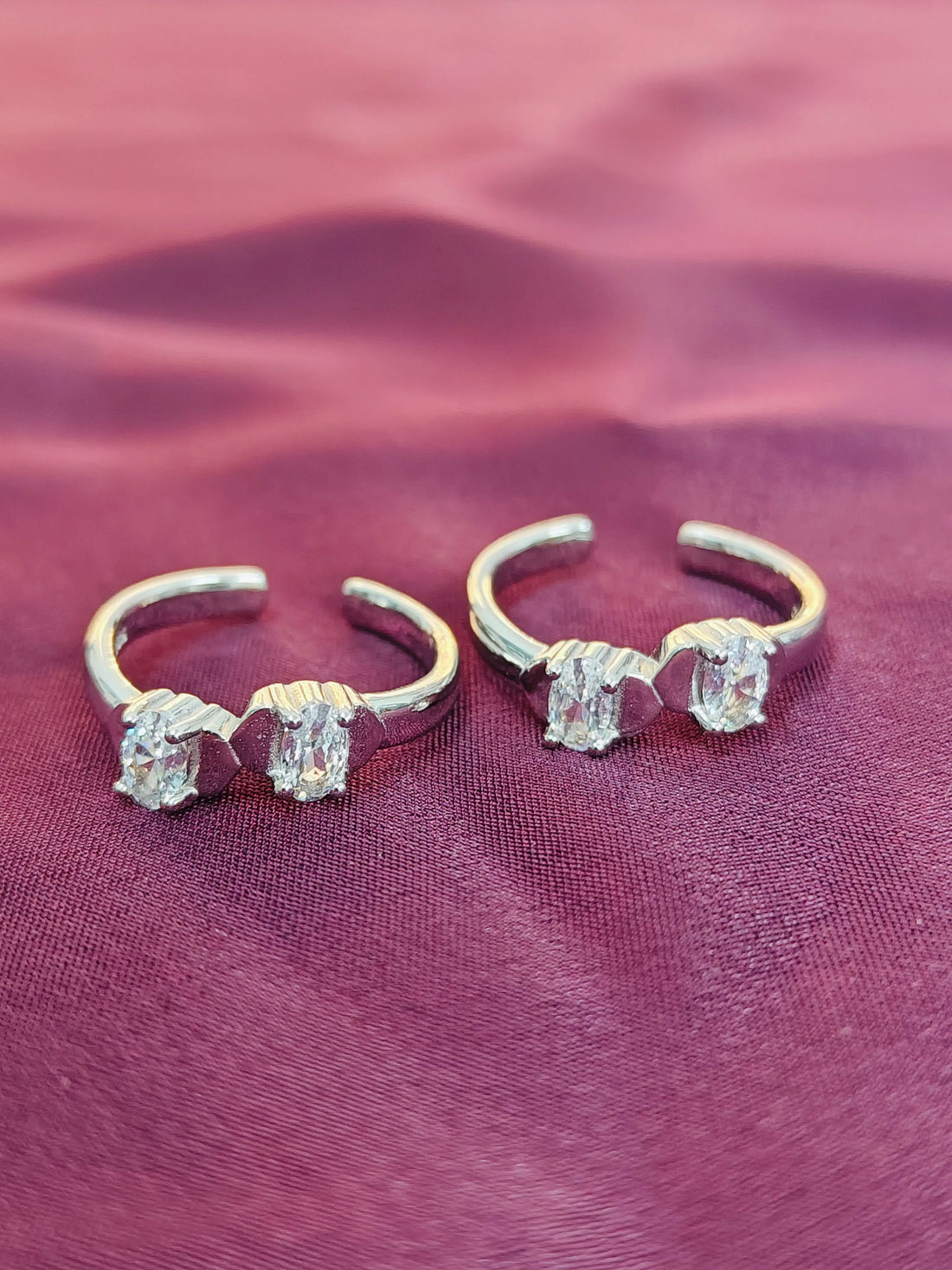 Pair of silver ear cuffs with gemstones on a purple fabric background