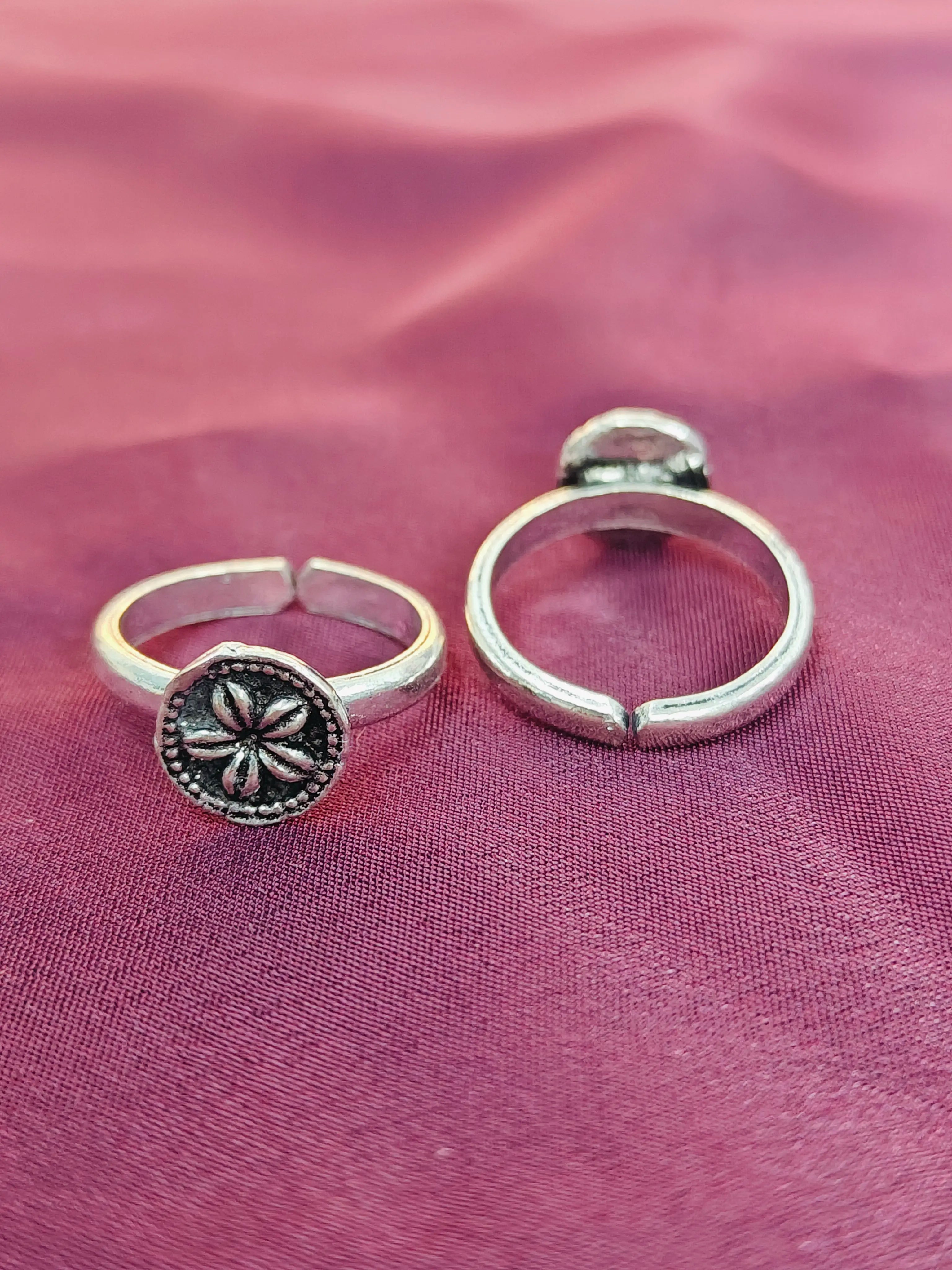 Two silver rings on a pink fabric background