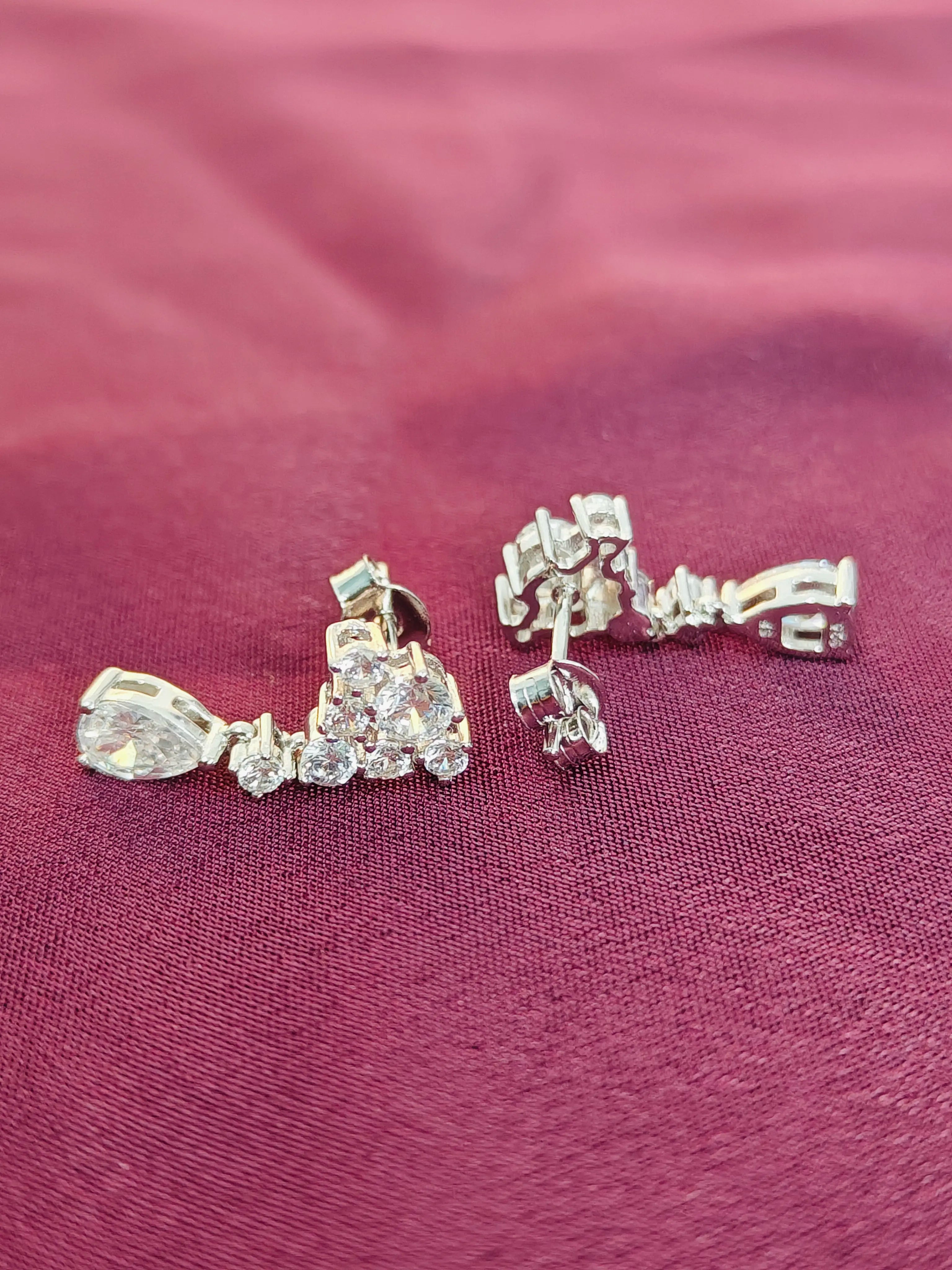 Pair of diamond earrings on a burgundy fabric background