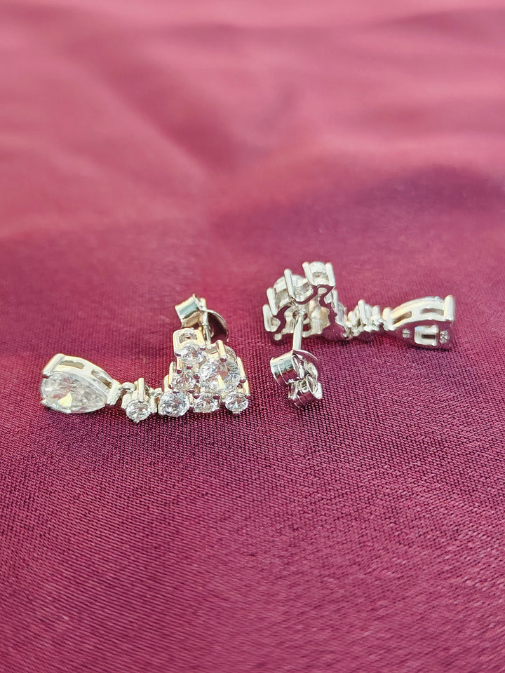 Pair of diamond earrings on a burgundy fabric background