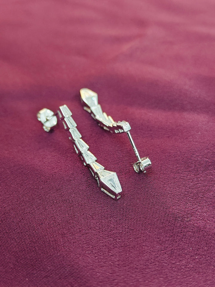 Pair of silver earrings on a purple fabric background