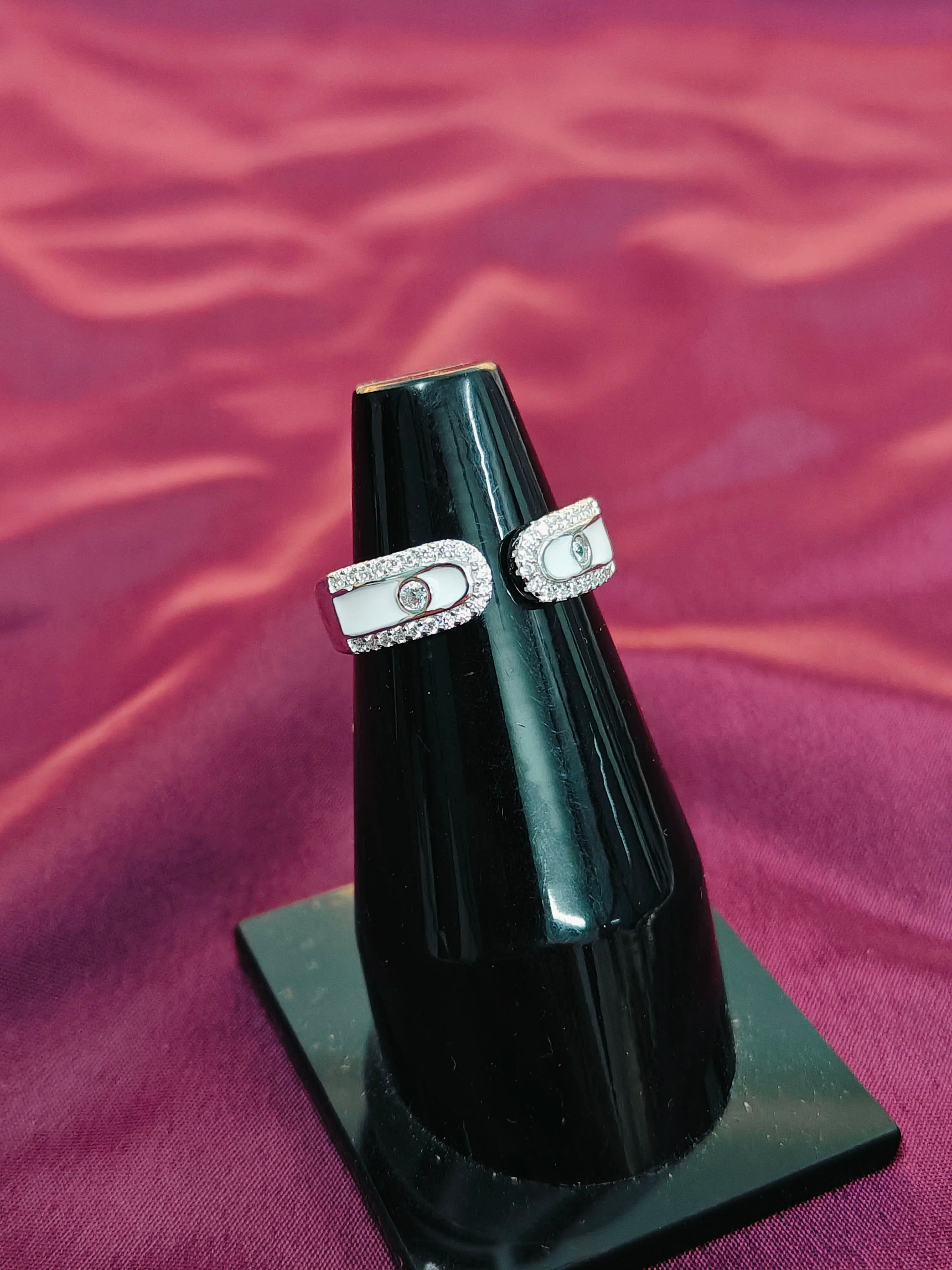 Pair of diamond earrings on a black stand against a red fabric background