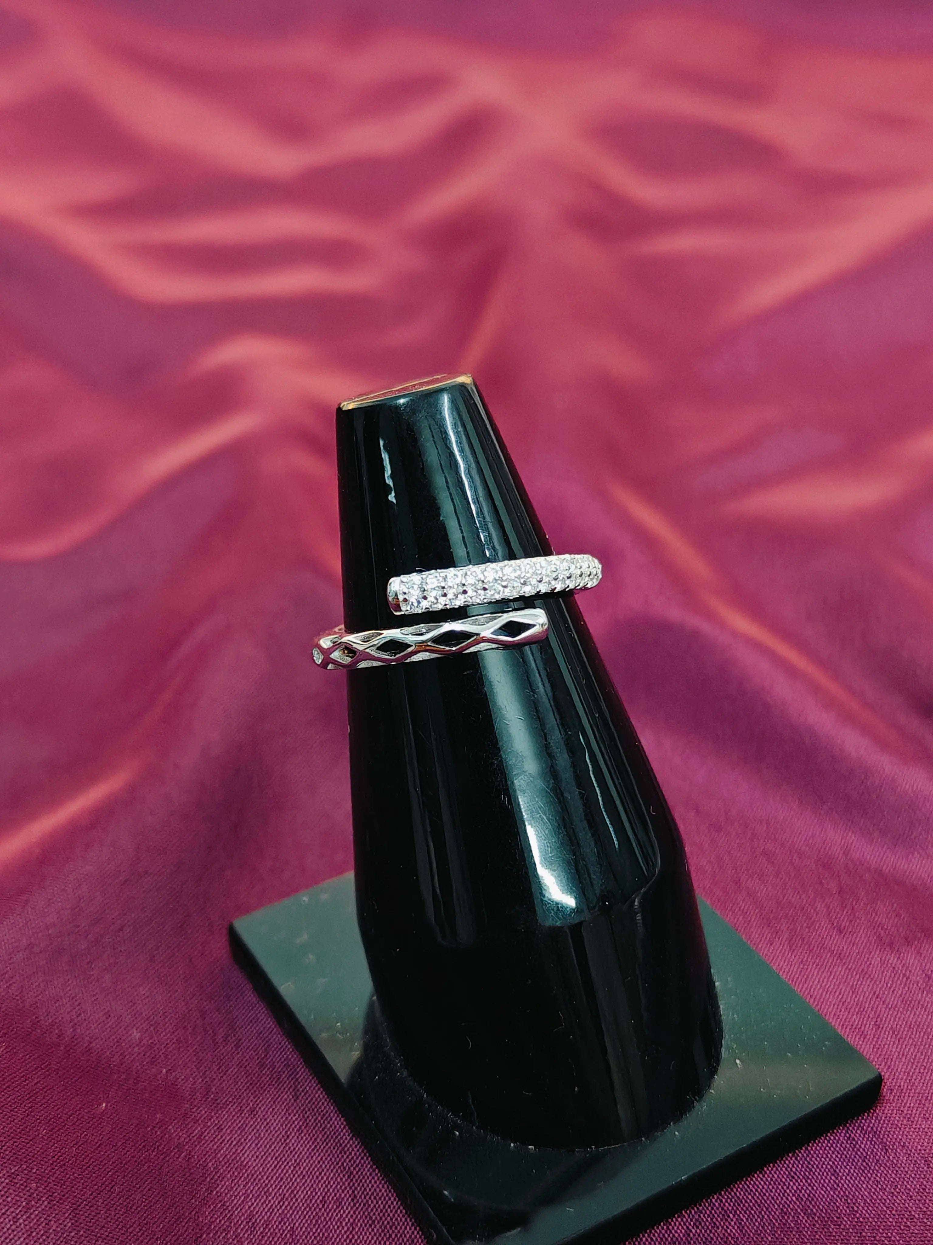 Two rings on a black stand against a purple fabric background