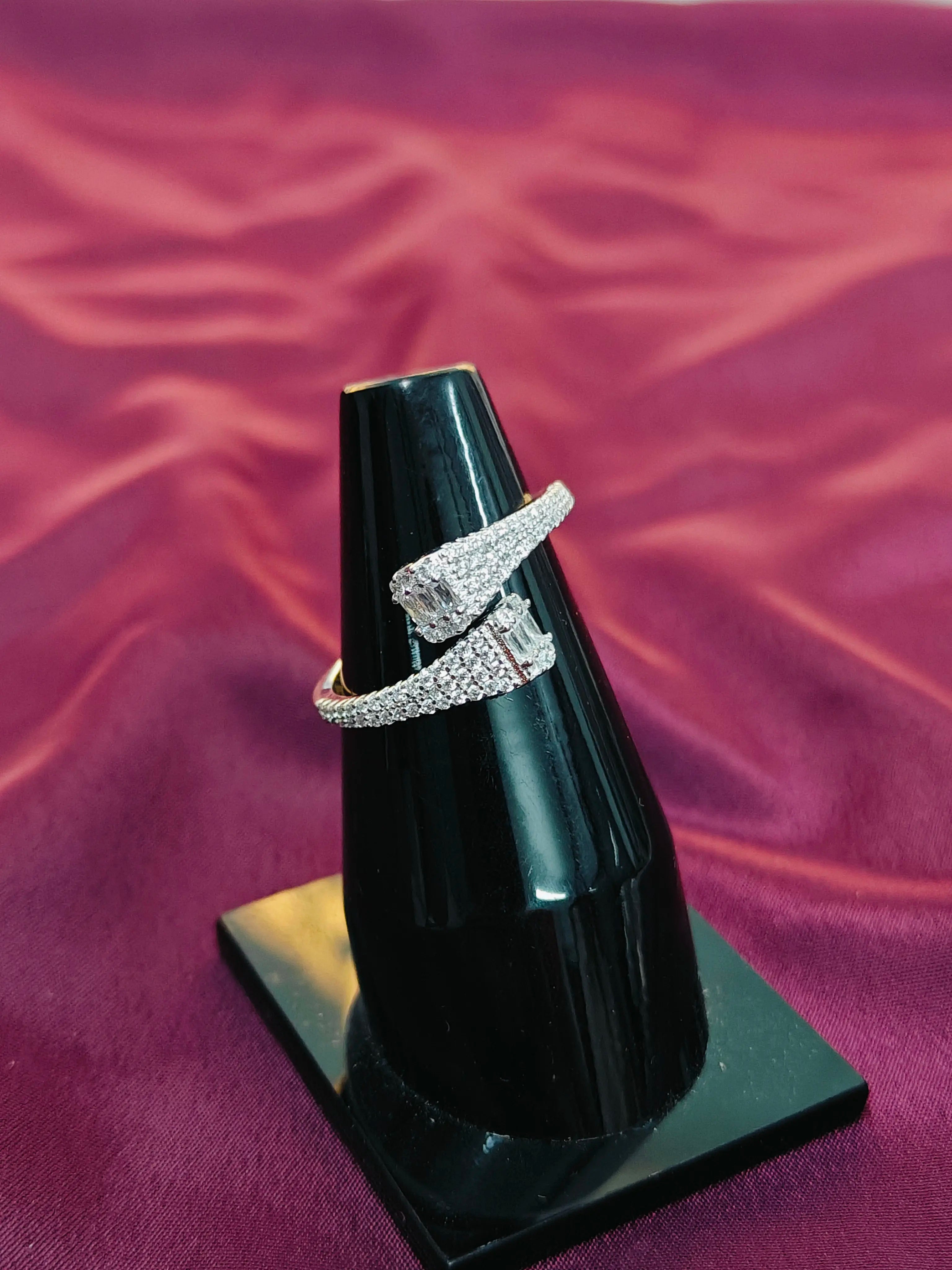 Silver ring on a black stand against a purple fabric background