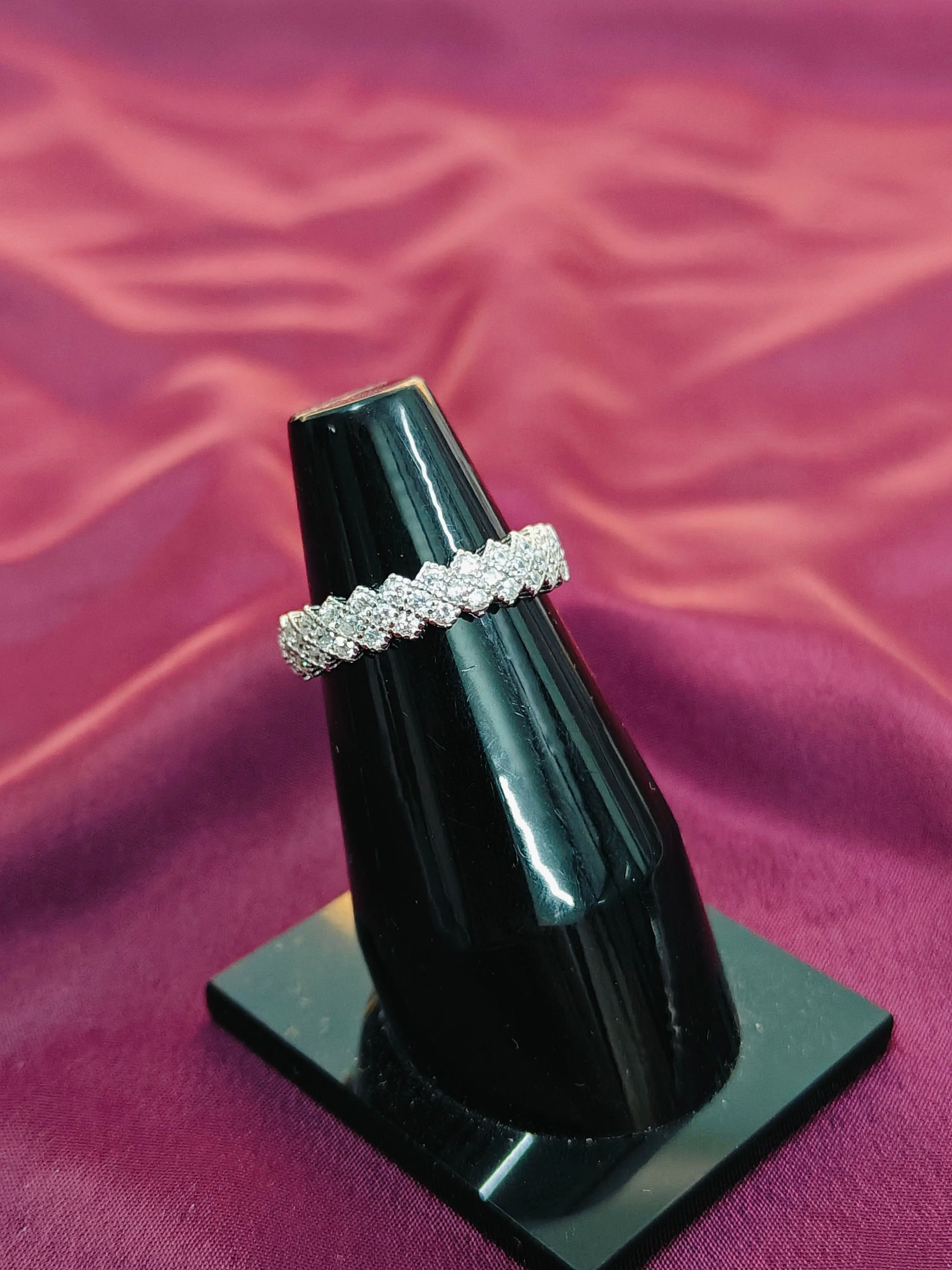 Diamond ring on a black stand against a purple fabric background