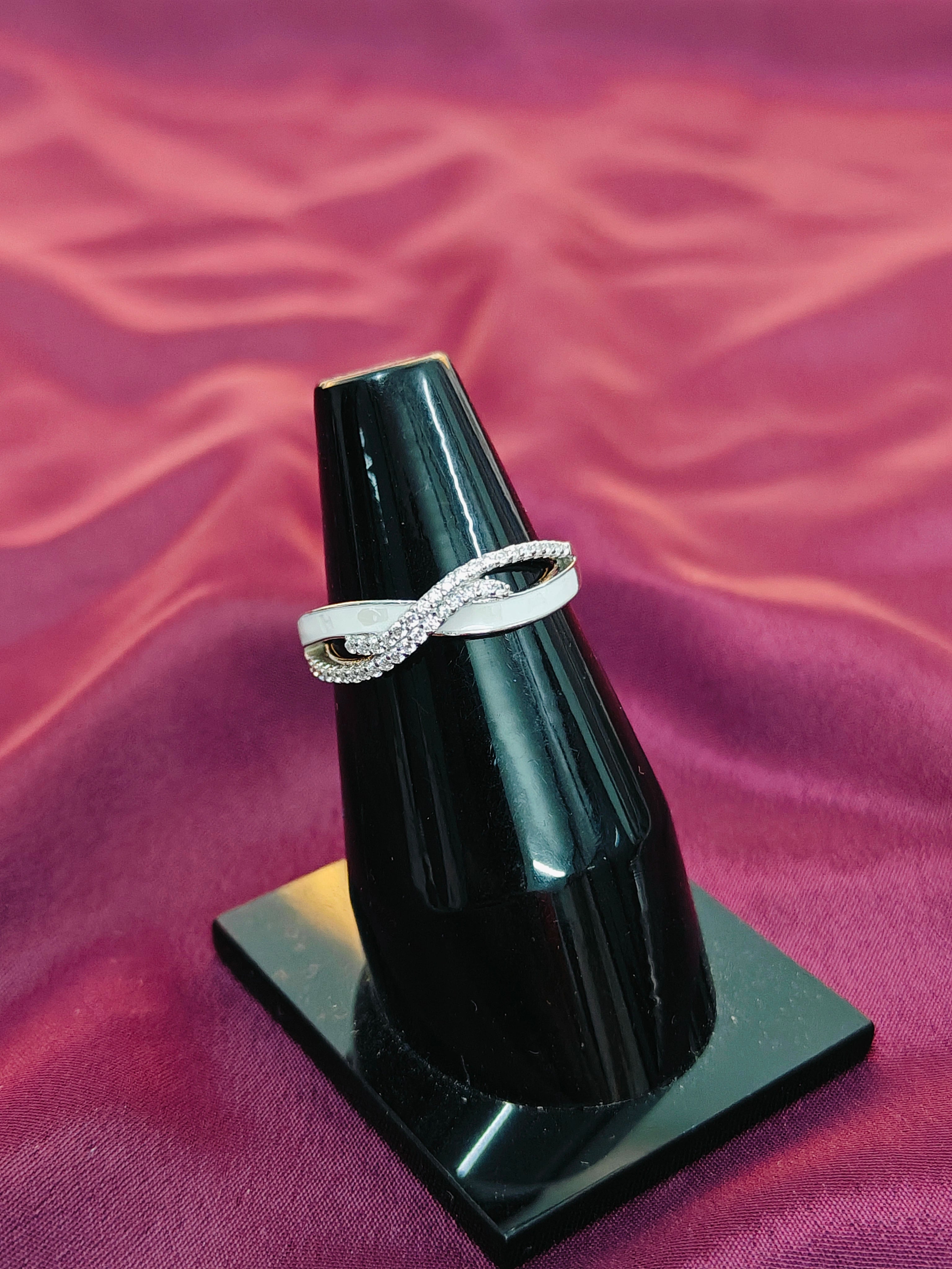 Silver ring on a black stand against a purple fabric background