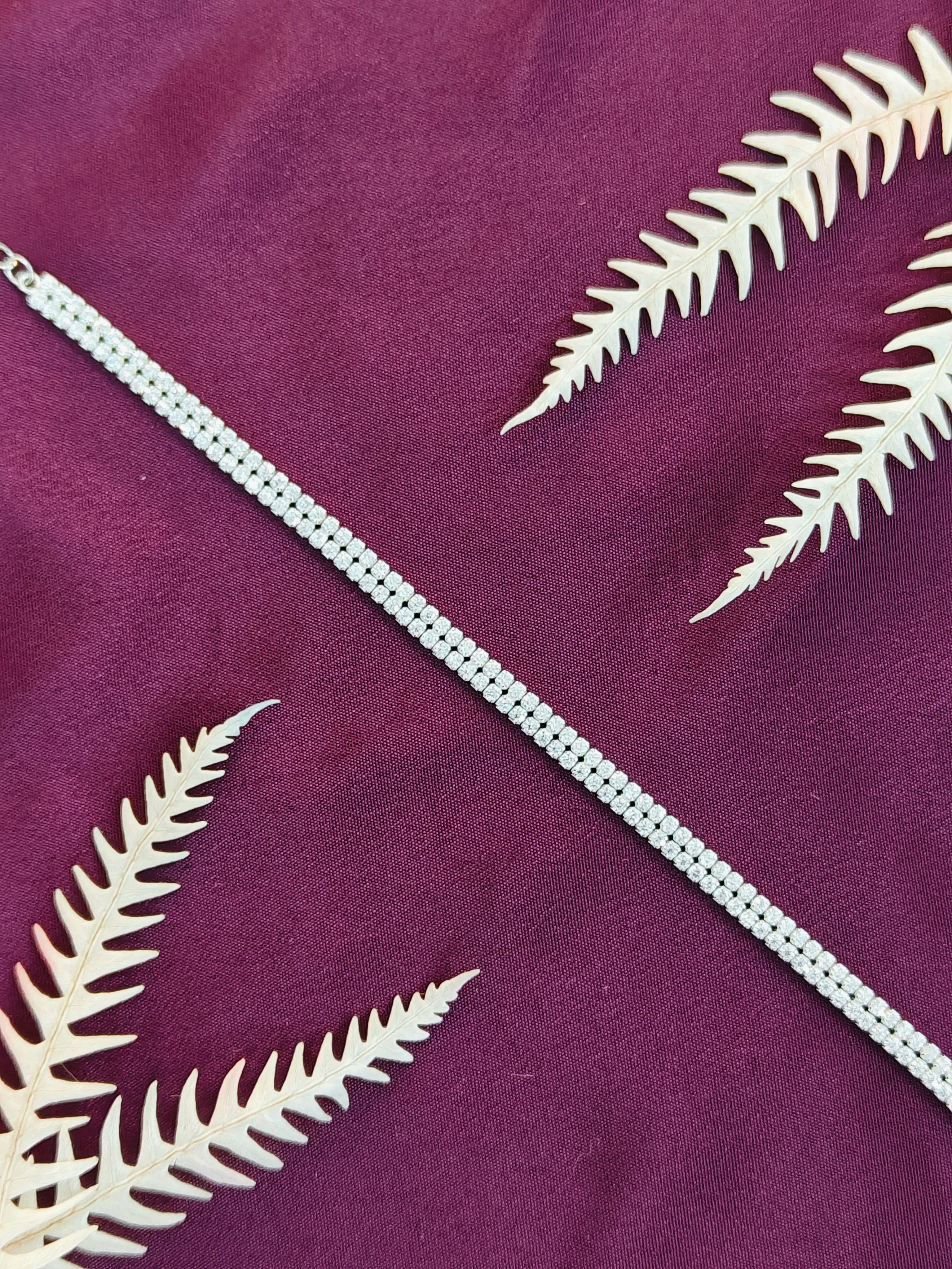 White fern leaves on a purple fabric background