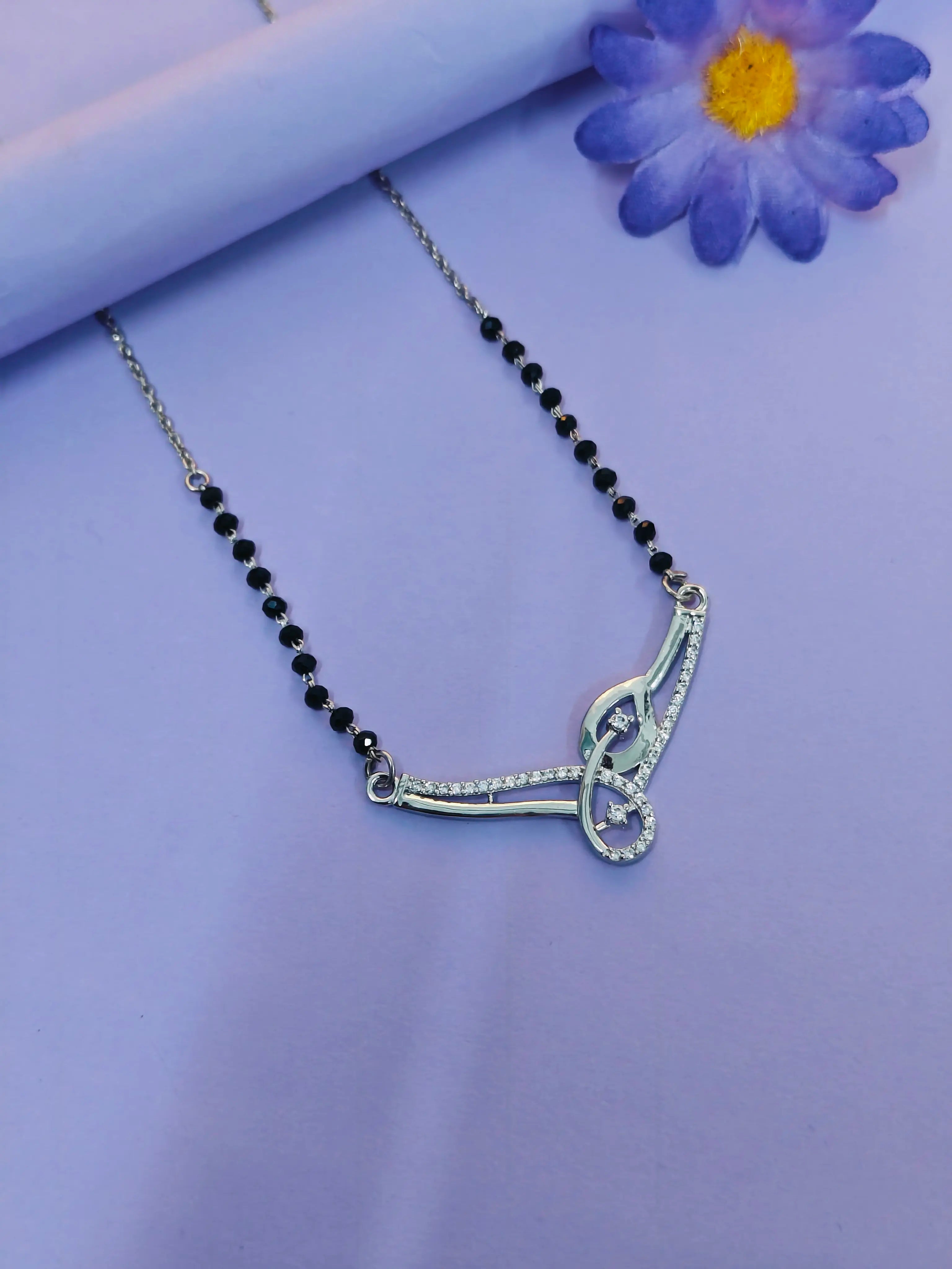 Silver necklace with black beads on a purple background