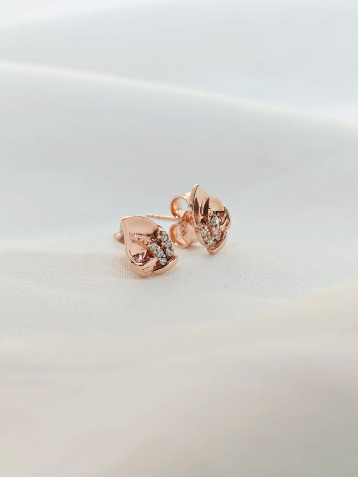 Rose gold earrings with clear gemstones on a light gray background
