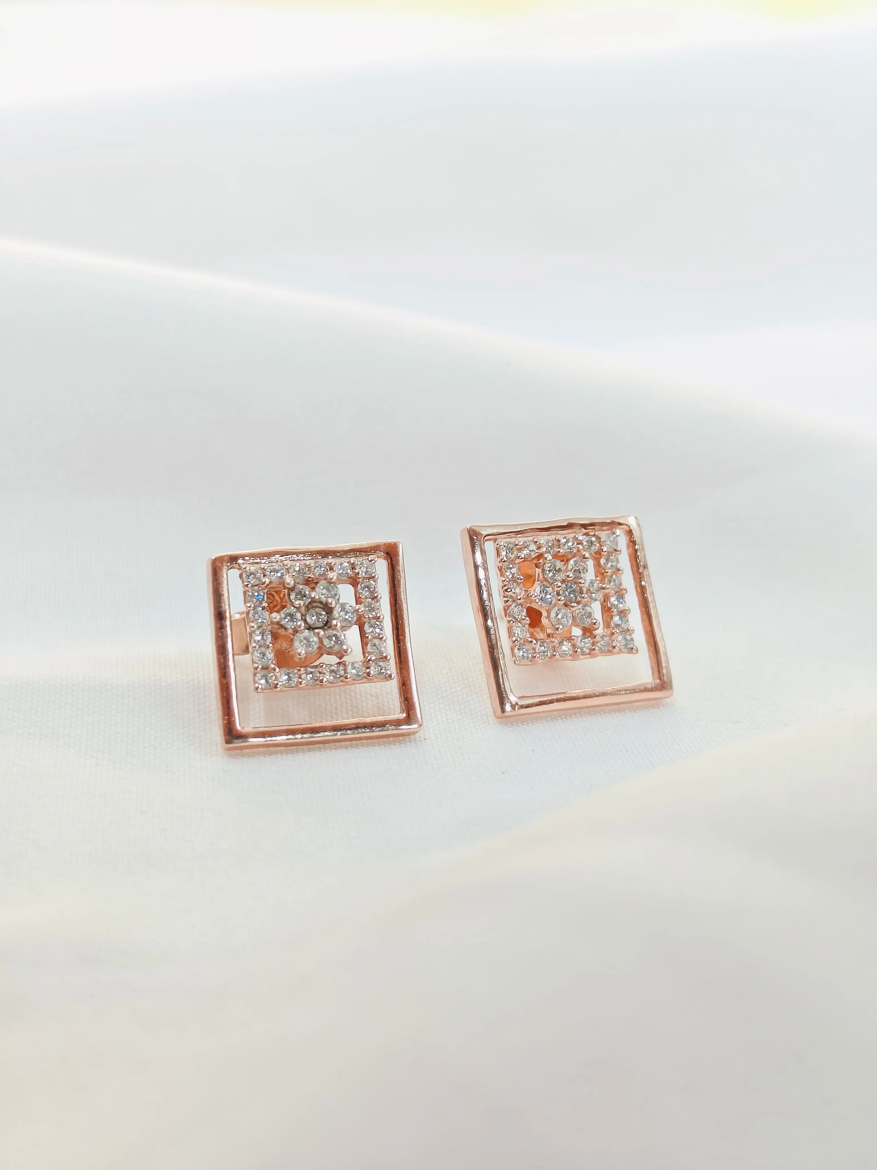 Rose gold square earrings with clear stones on a light gray background