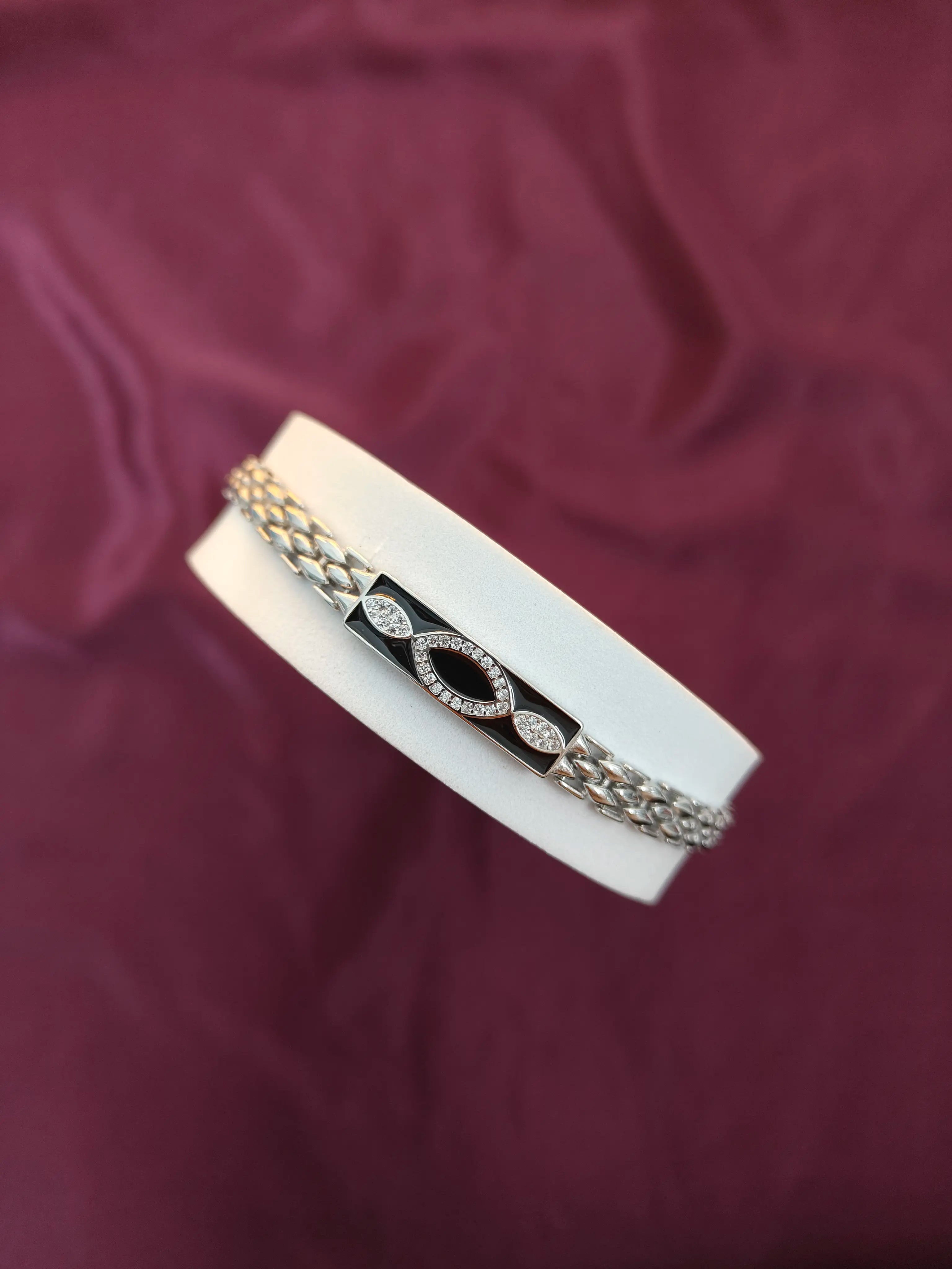 Two bracelets on a white stand against a purple fabric background