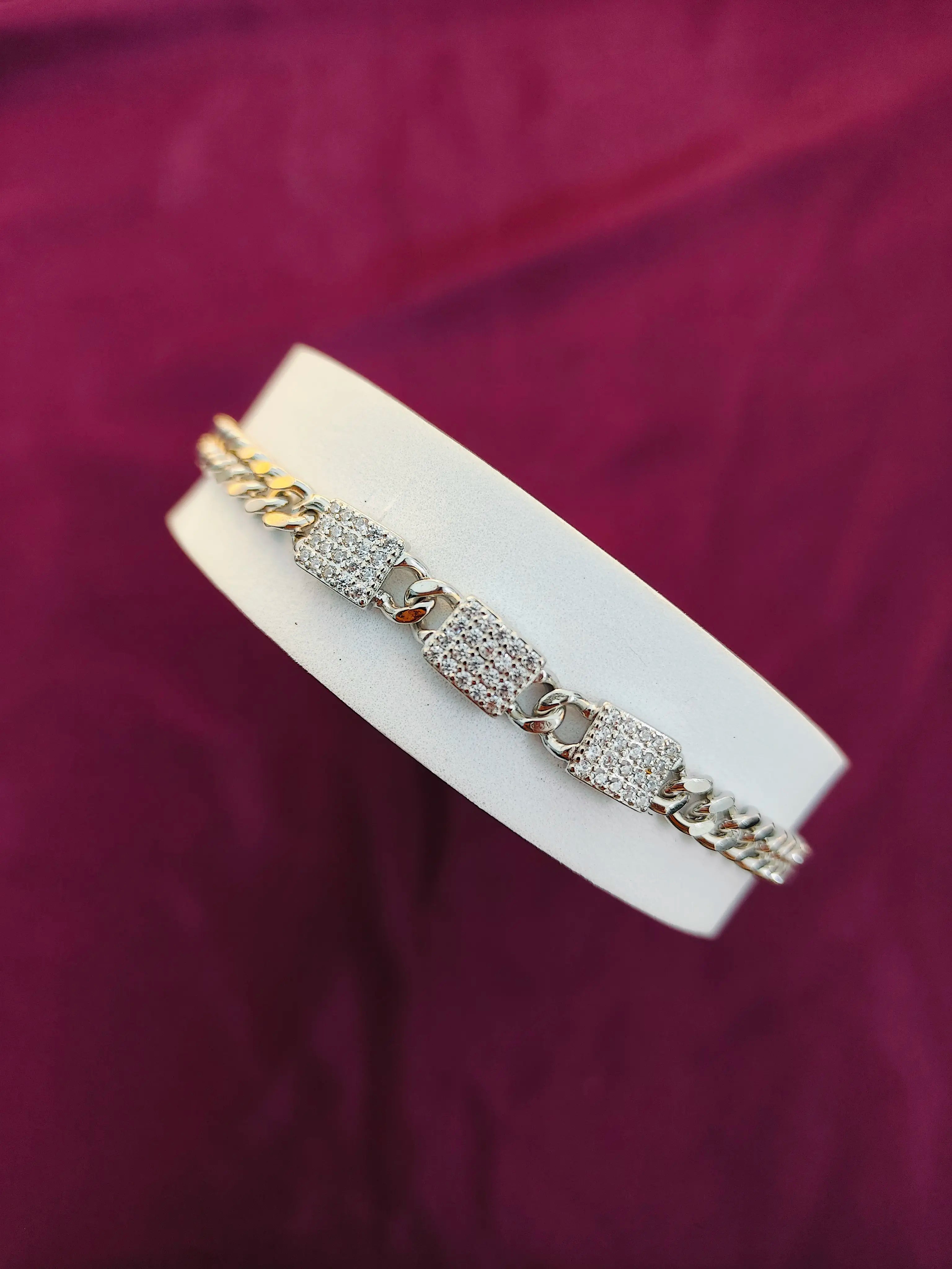 Gold and silver bracelet on a white stand against a purple background