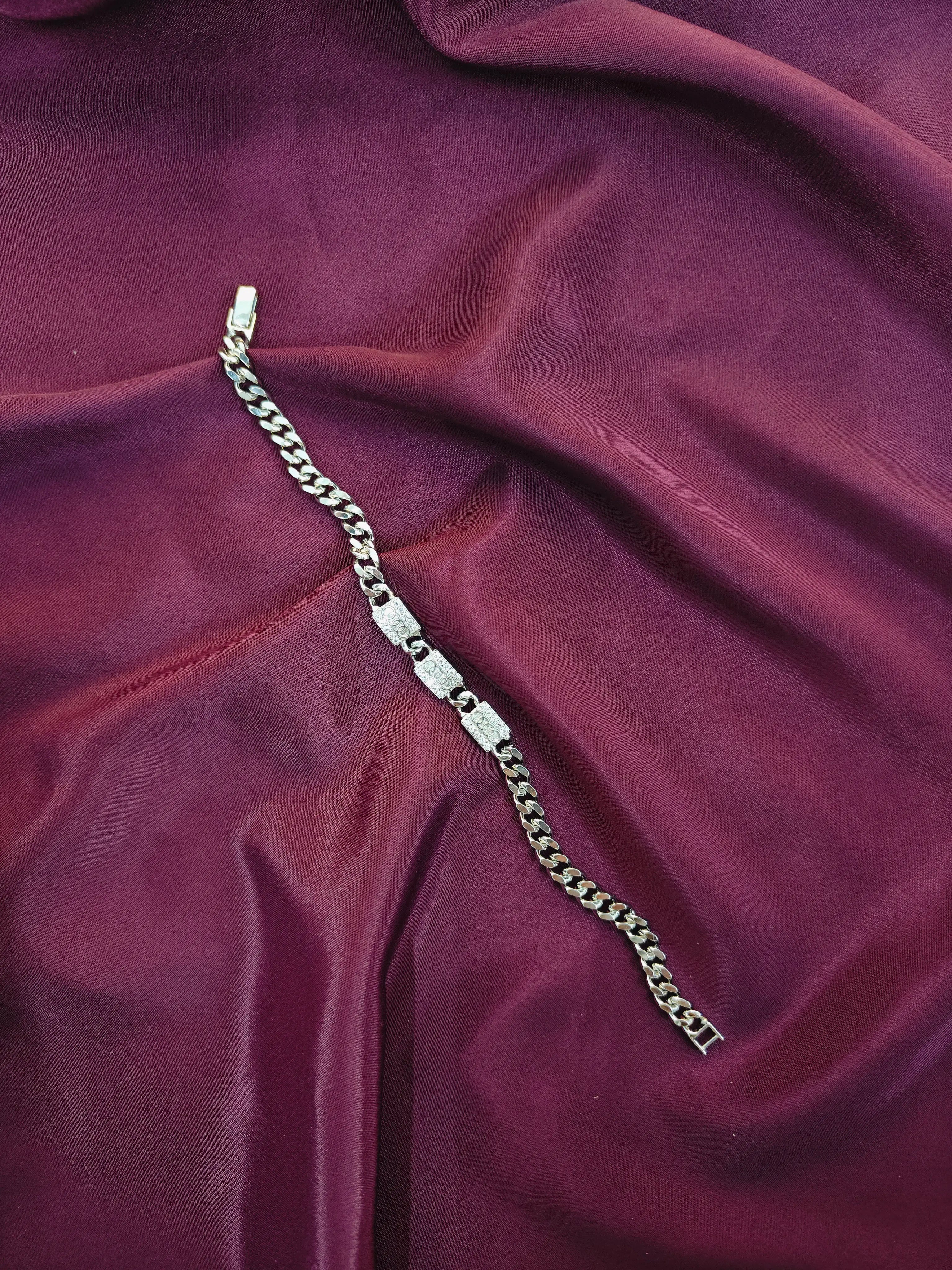Silver chain bracelet on a purple fabric background