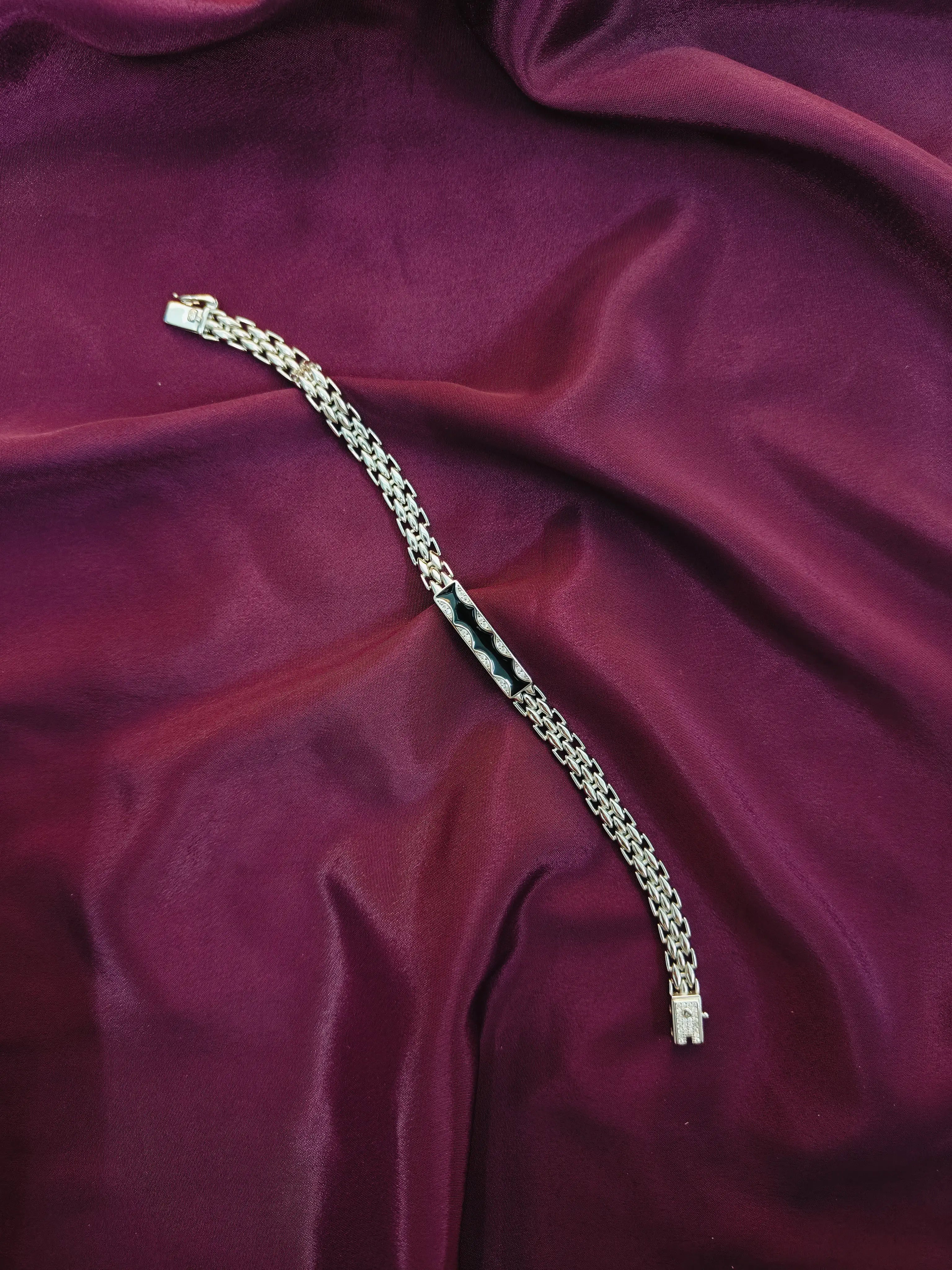 Silver chain bracelet on a maroon fabric background