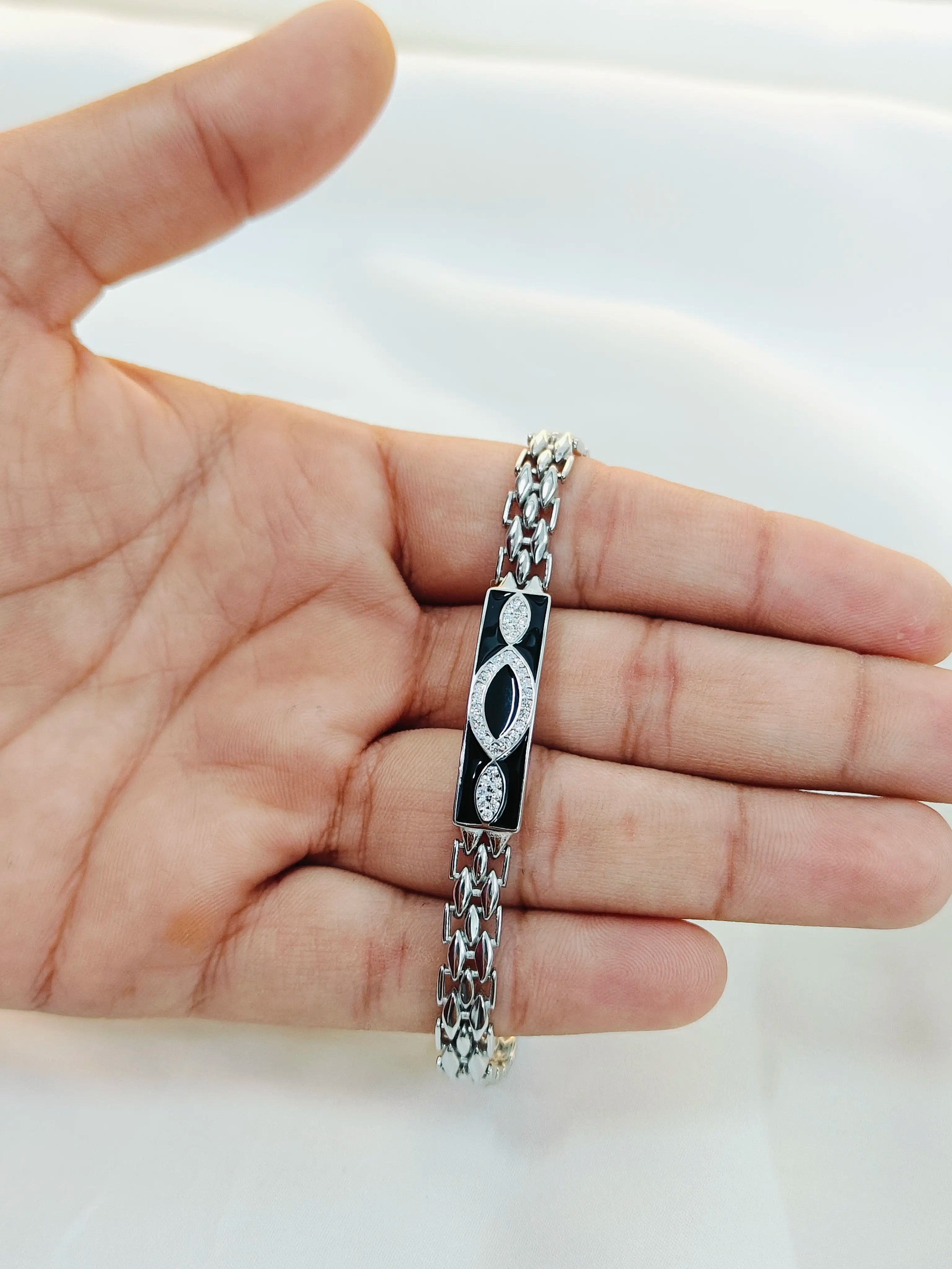 Silver bracelet with black accents on a hand against a white background