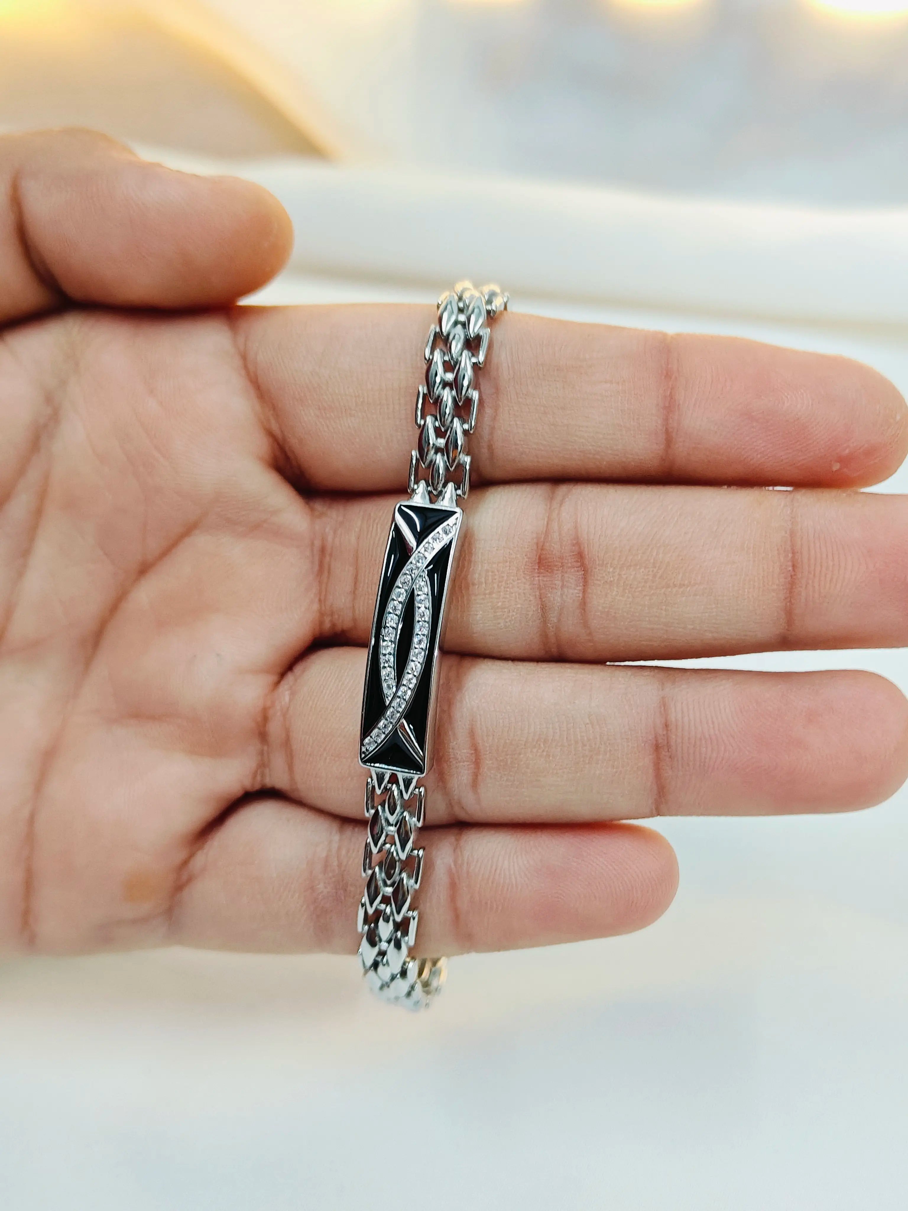 Silver bracelet with intricate design on a hand against a neutral background