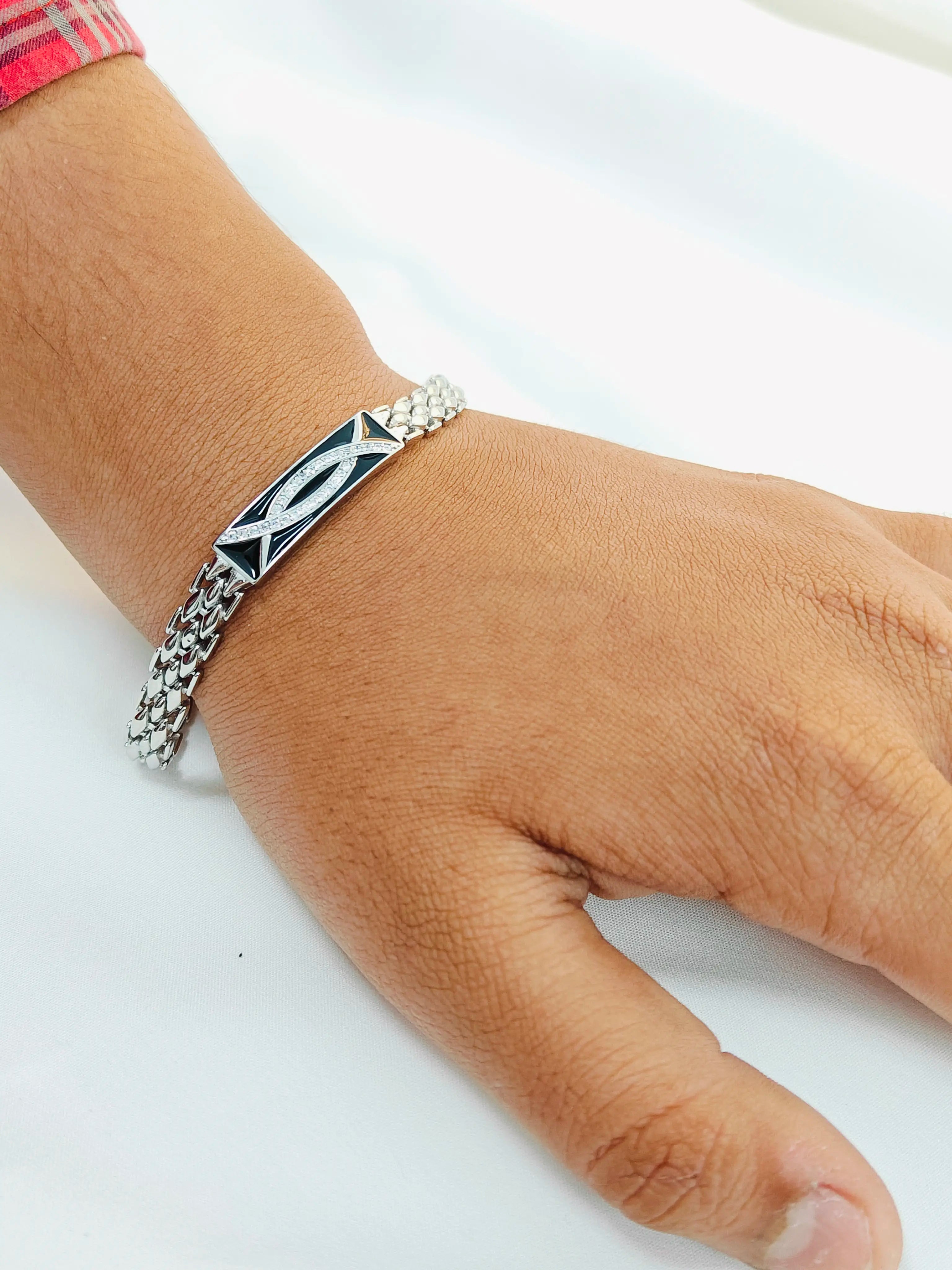 Silver bracelet with a geometric design on a wrist against a white background