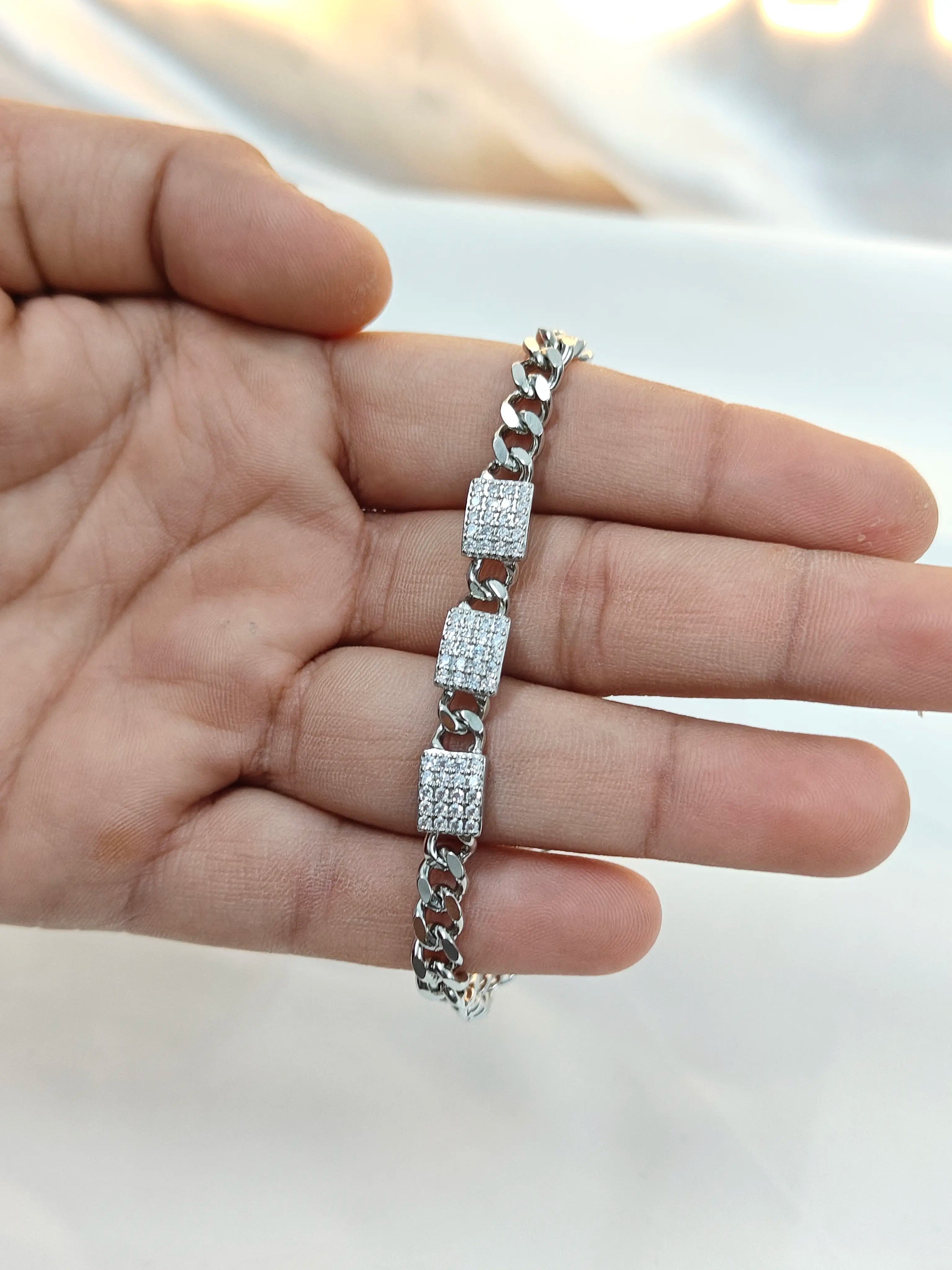 Silver bracelet with diamond accents on a hand against a neutral background