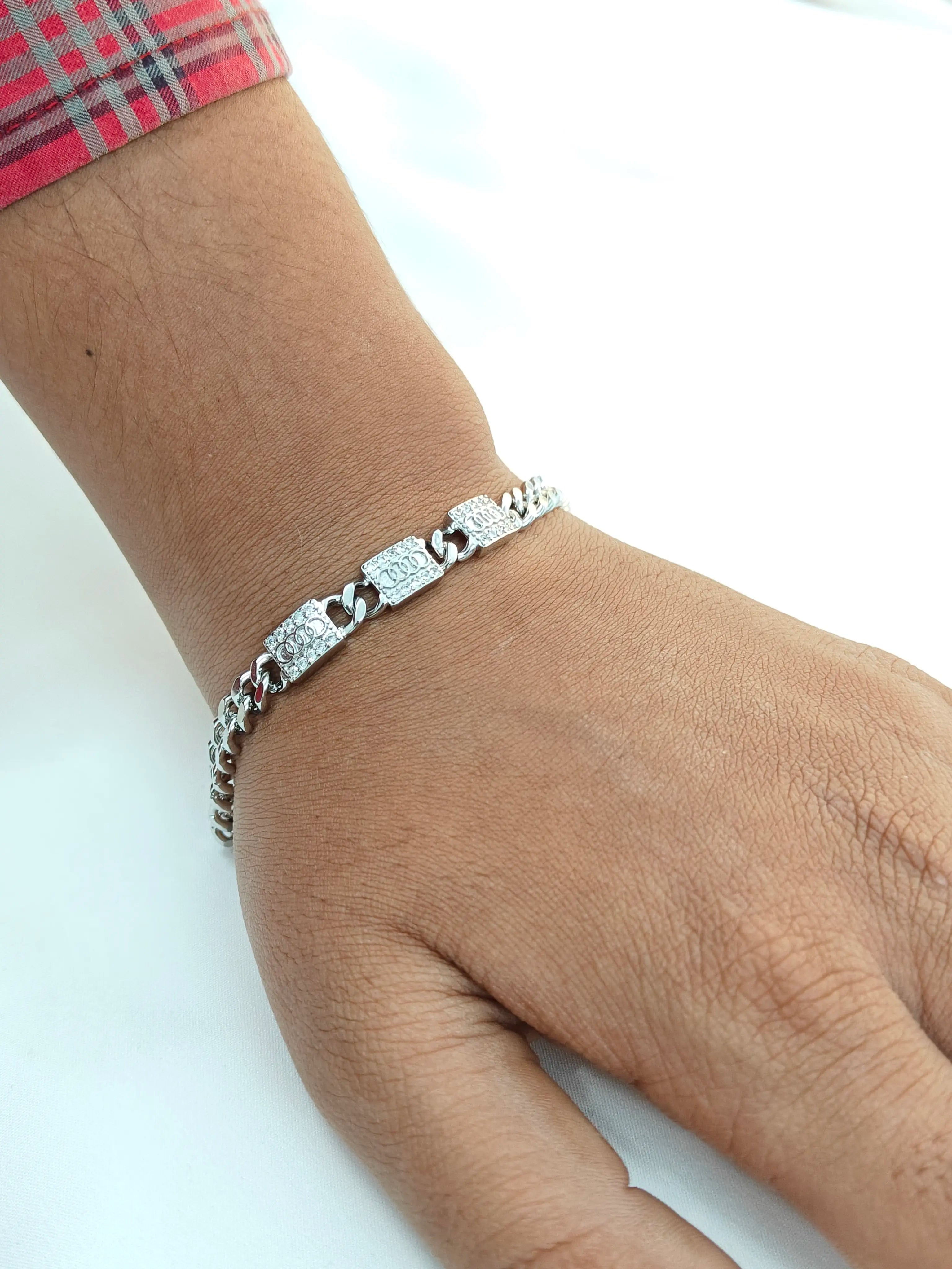Silver bracelet on a wrist with a plain background