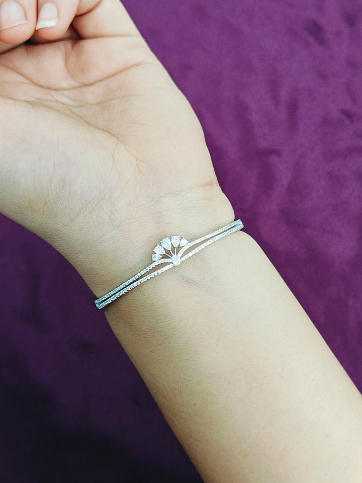 Silver bracelet on a wrist with a purple background
