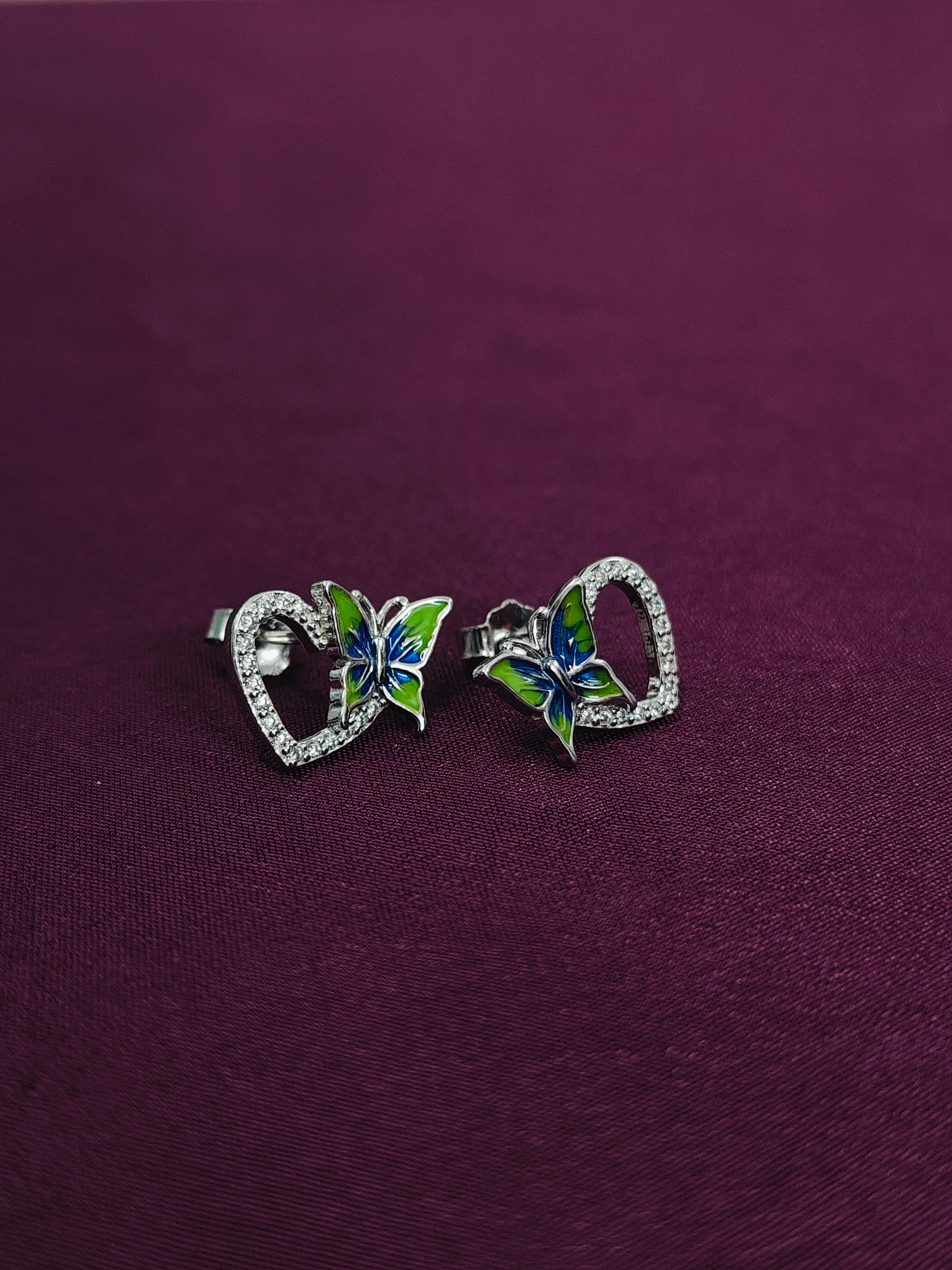 Butterfly-shaped earrings on a purple background