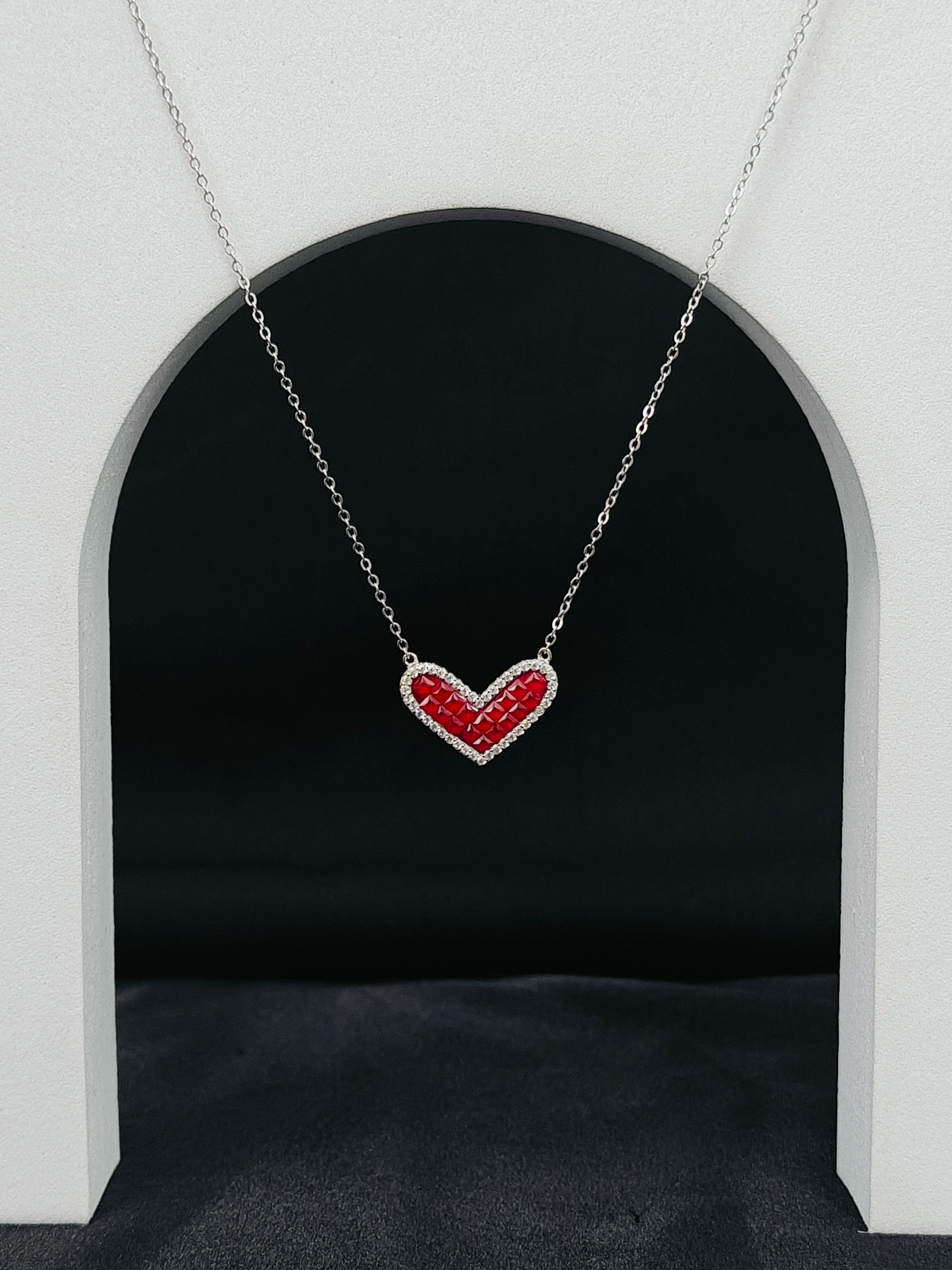Heart-shaped necklace with red and silver design on a dark background